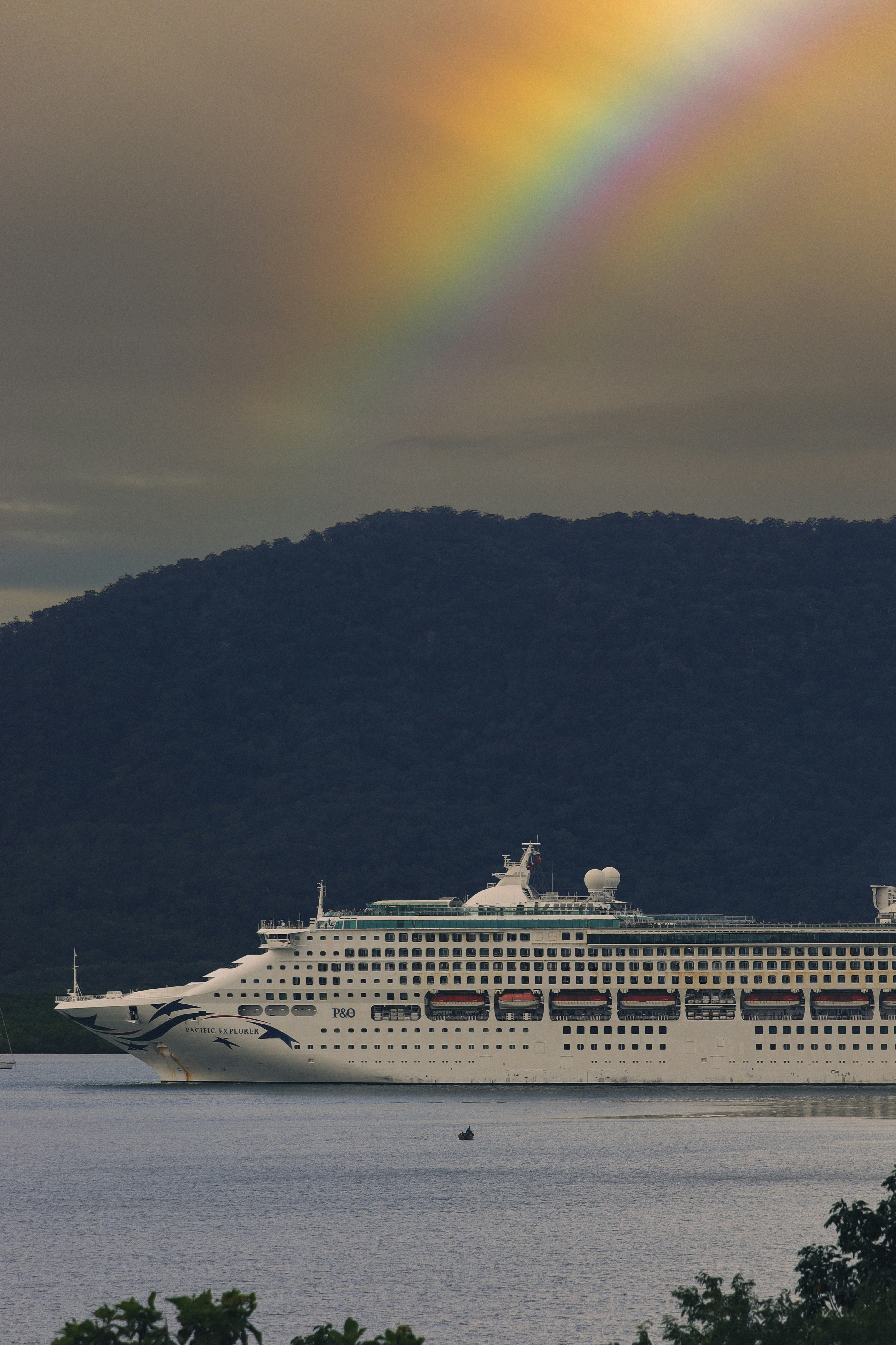 A cruise ship with a rainbow in the background