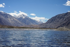 A body of water surrounded by mountains under a blue sky