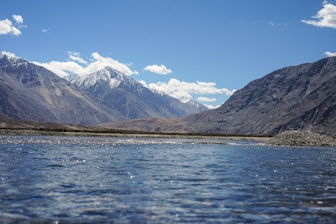 A body of water surrounded by mountains under a blue sky
