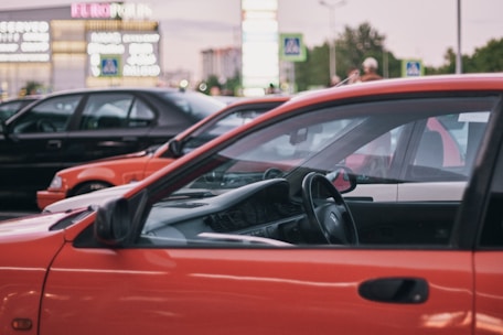 A red car parked in a parking lot next to other cars