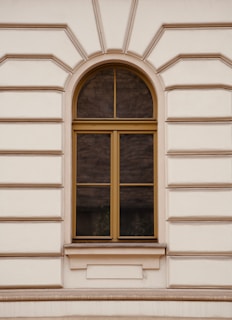 A white building with a window and a bench in front of it