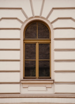A white building with a window and a bench in front of it