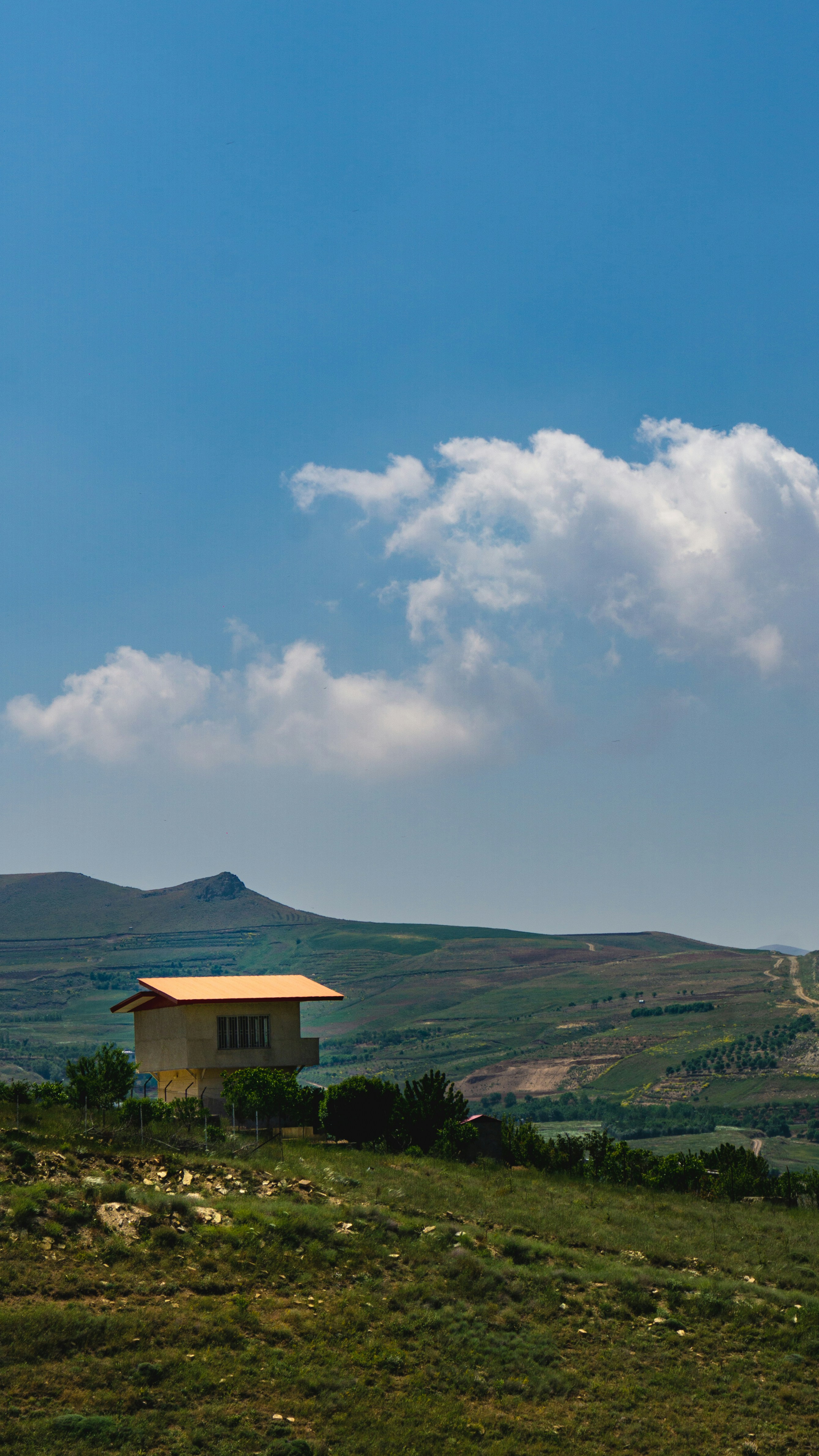 Una casa en una colina con un cielo azul al fondo