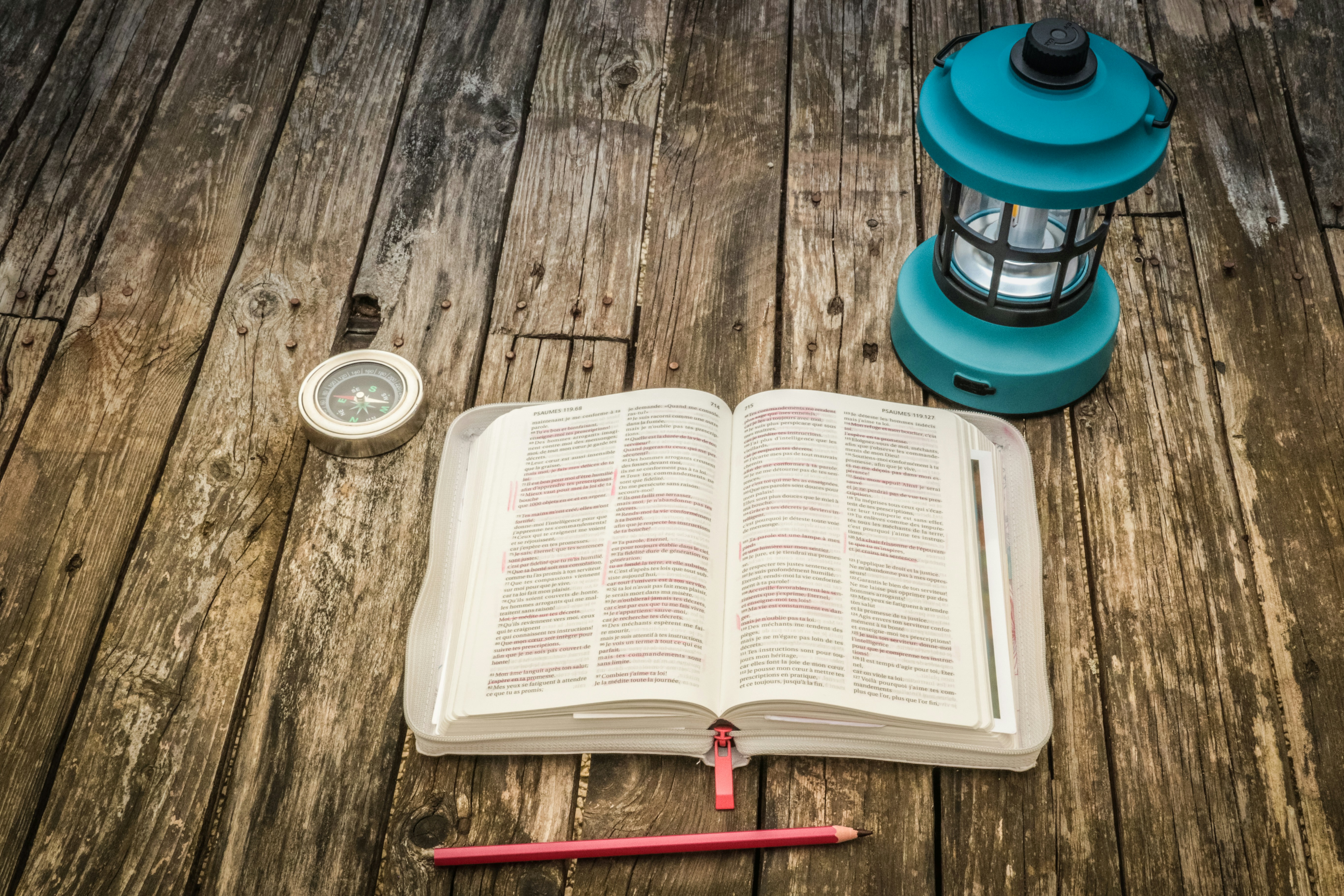 A book, a lamp, and a pencil on a wooden table
