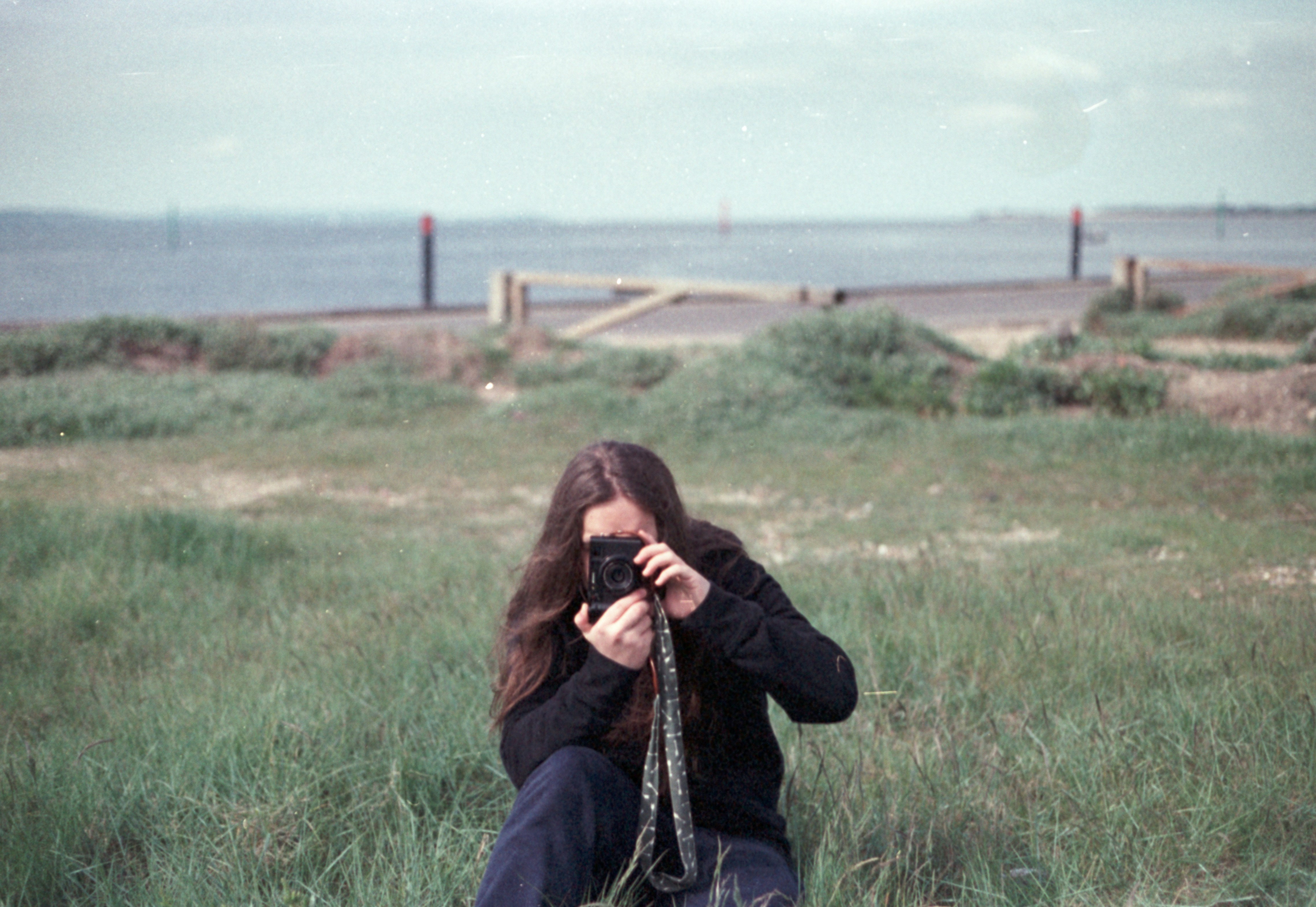 A woman sitting in a field with a camera