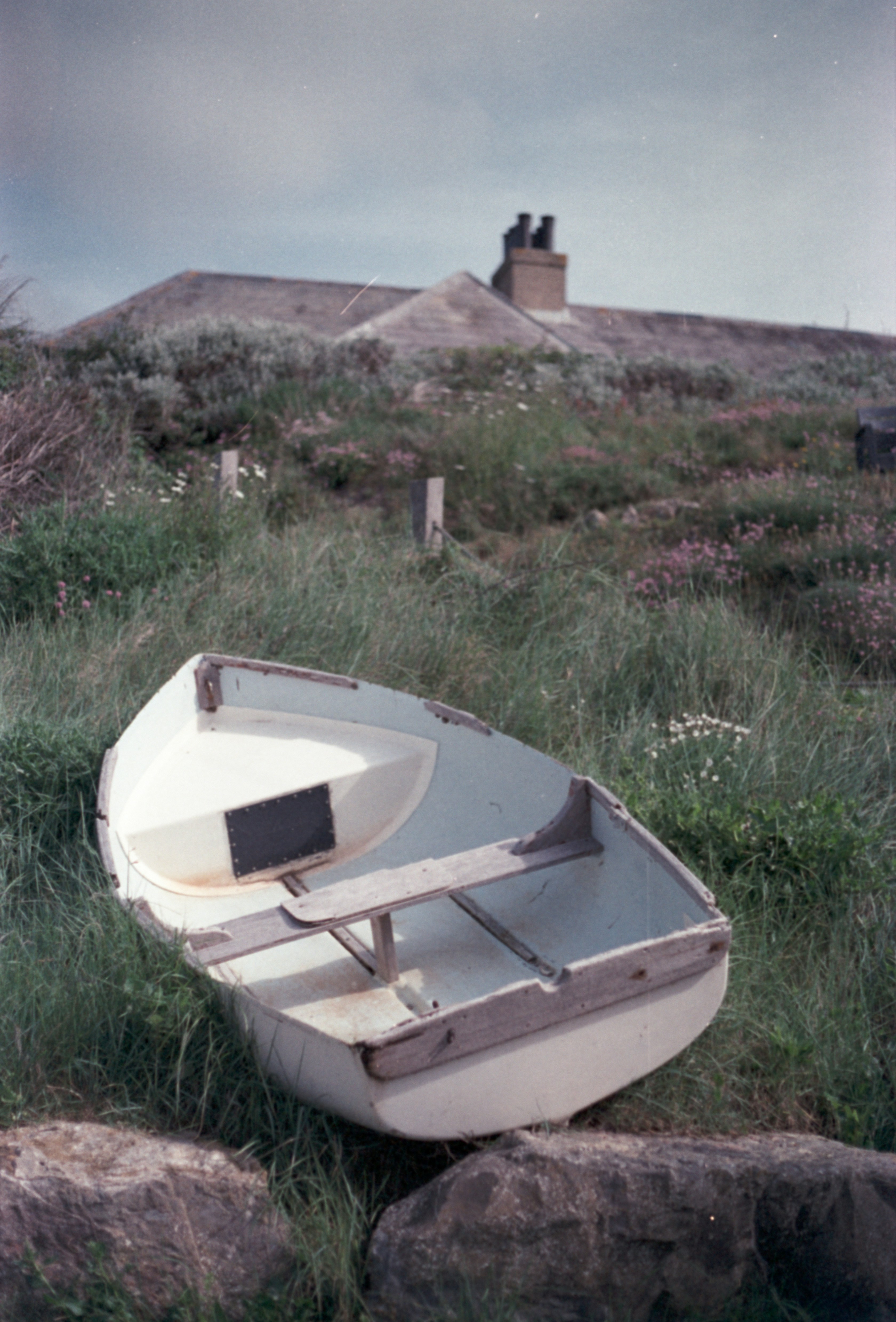 Um pequeno barco branco sentado no topo de um campo verde exuberante