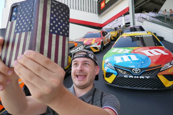 A man holding up a cell phone with a flag on it