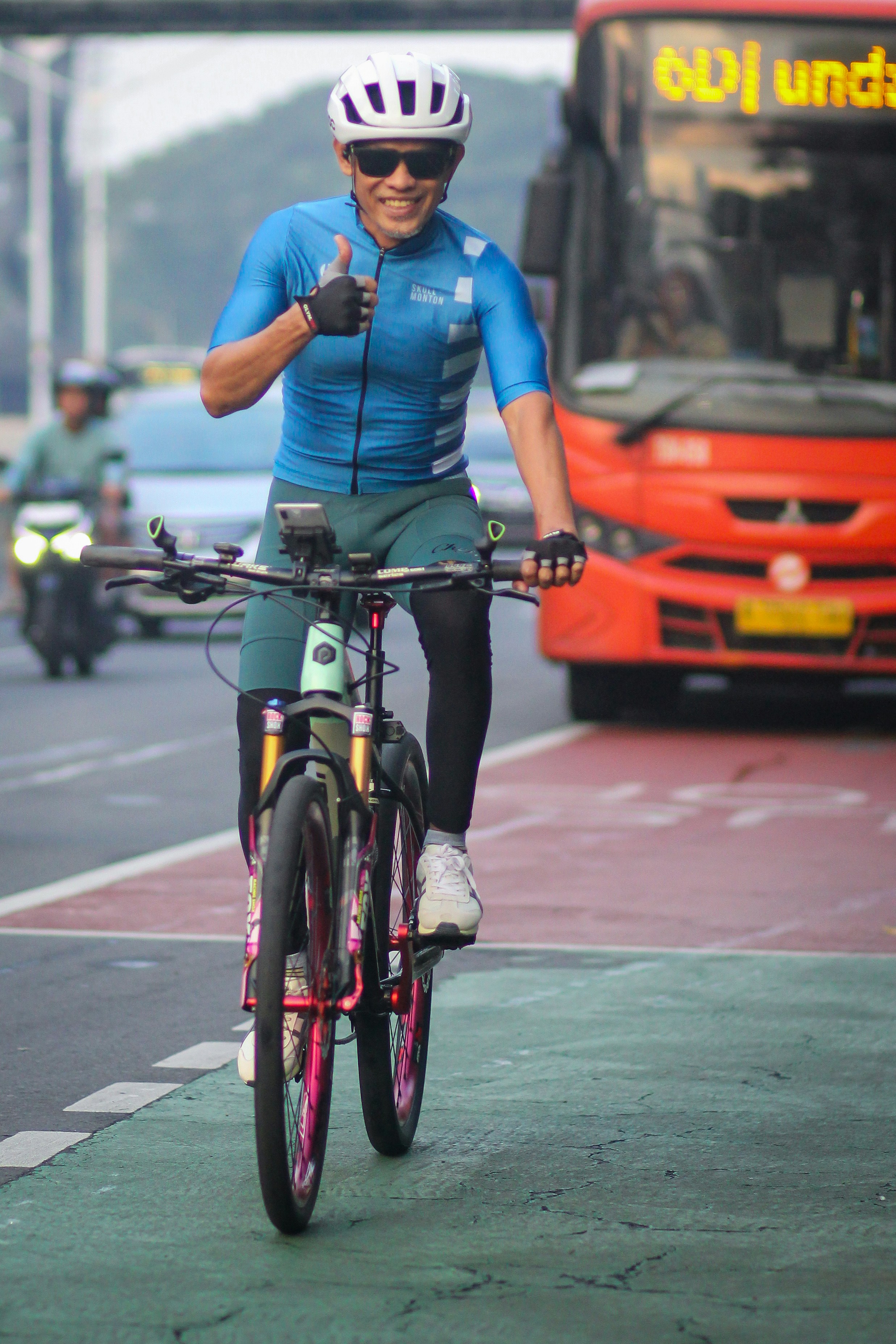 A man riding a bike down a street next to a bus