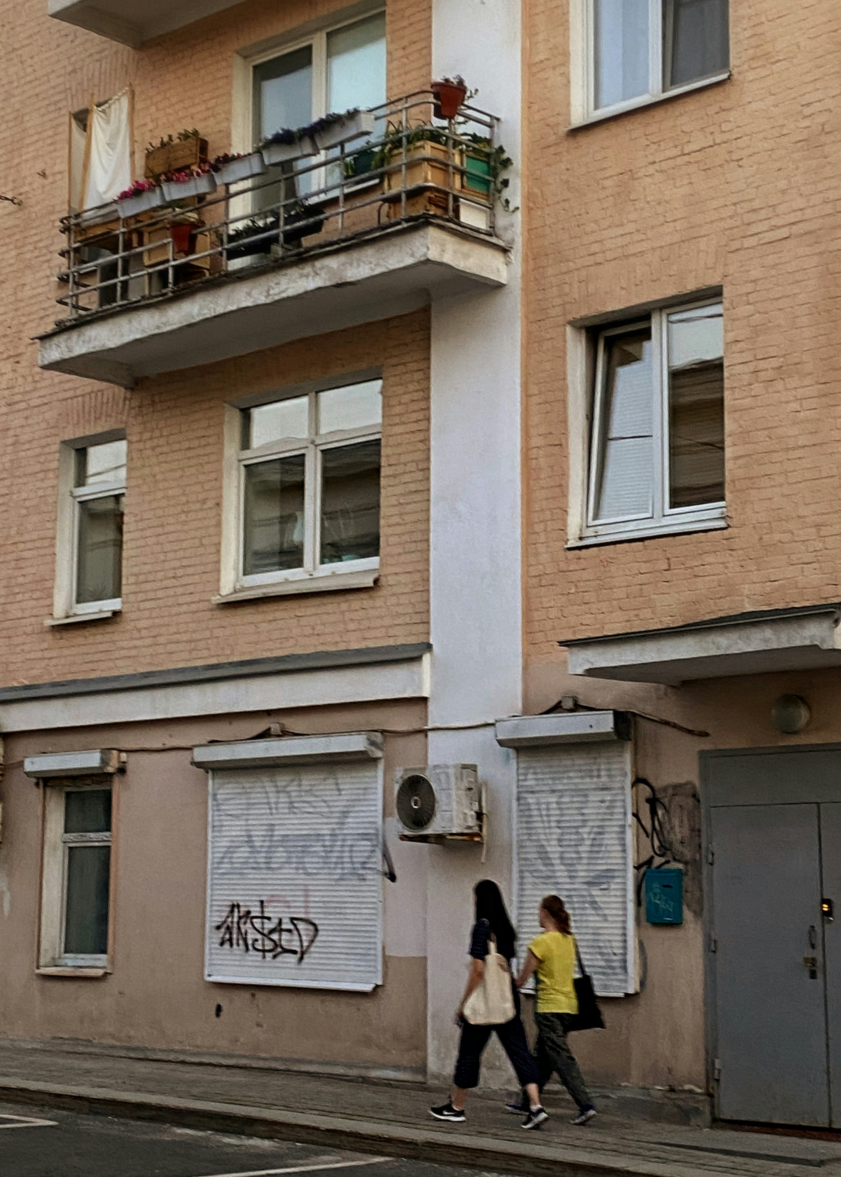 A couple of people walking down a street next to a tall building
