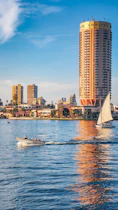 A sailboat in the water near a tall building