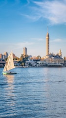 A sailboat on the water with a city in the background