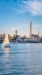 A sailboat on the water with a city in the background