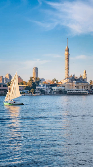A sailboat on the water with a city in the background