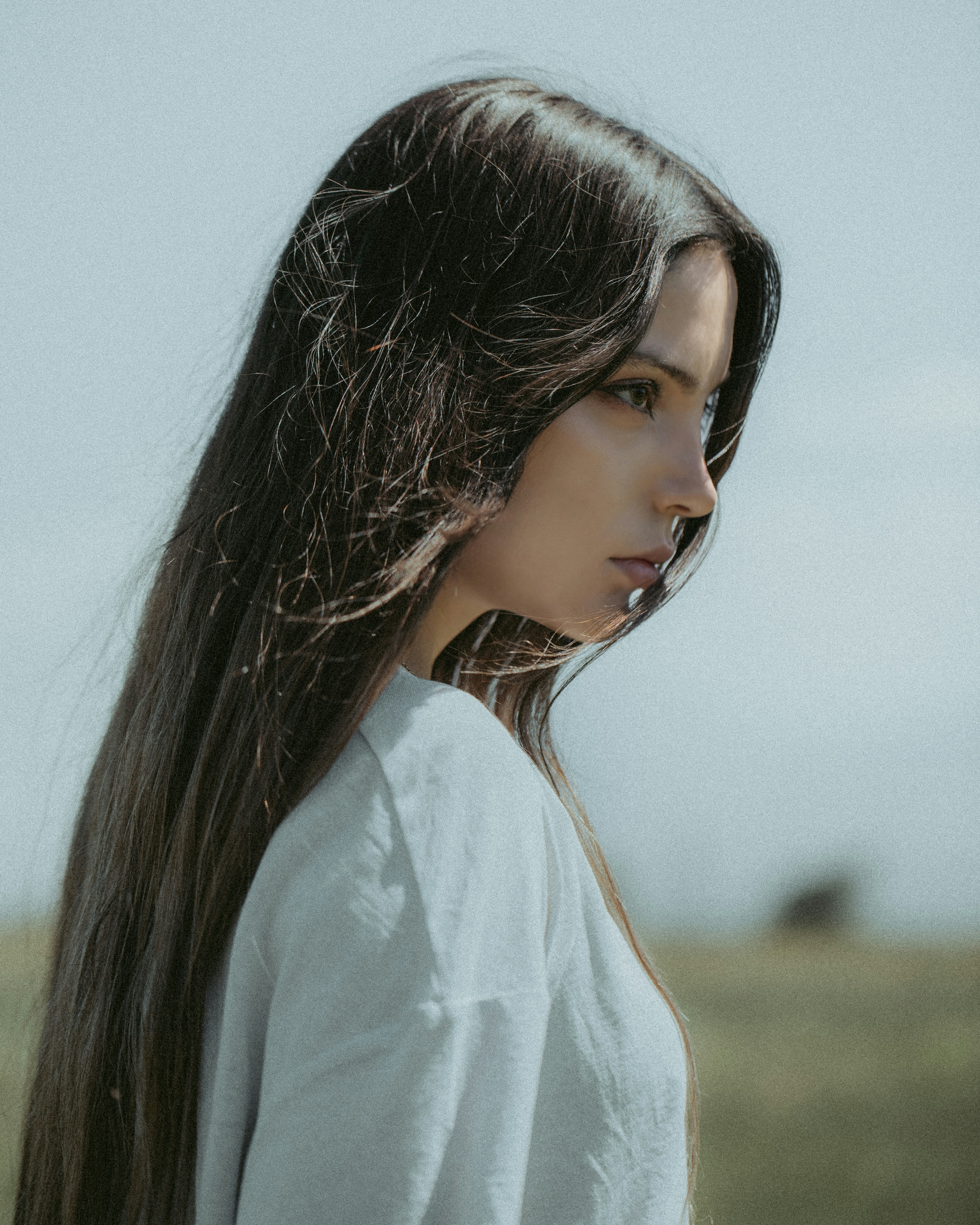 A woman with long hair standing in a field