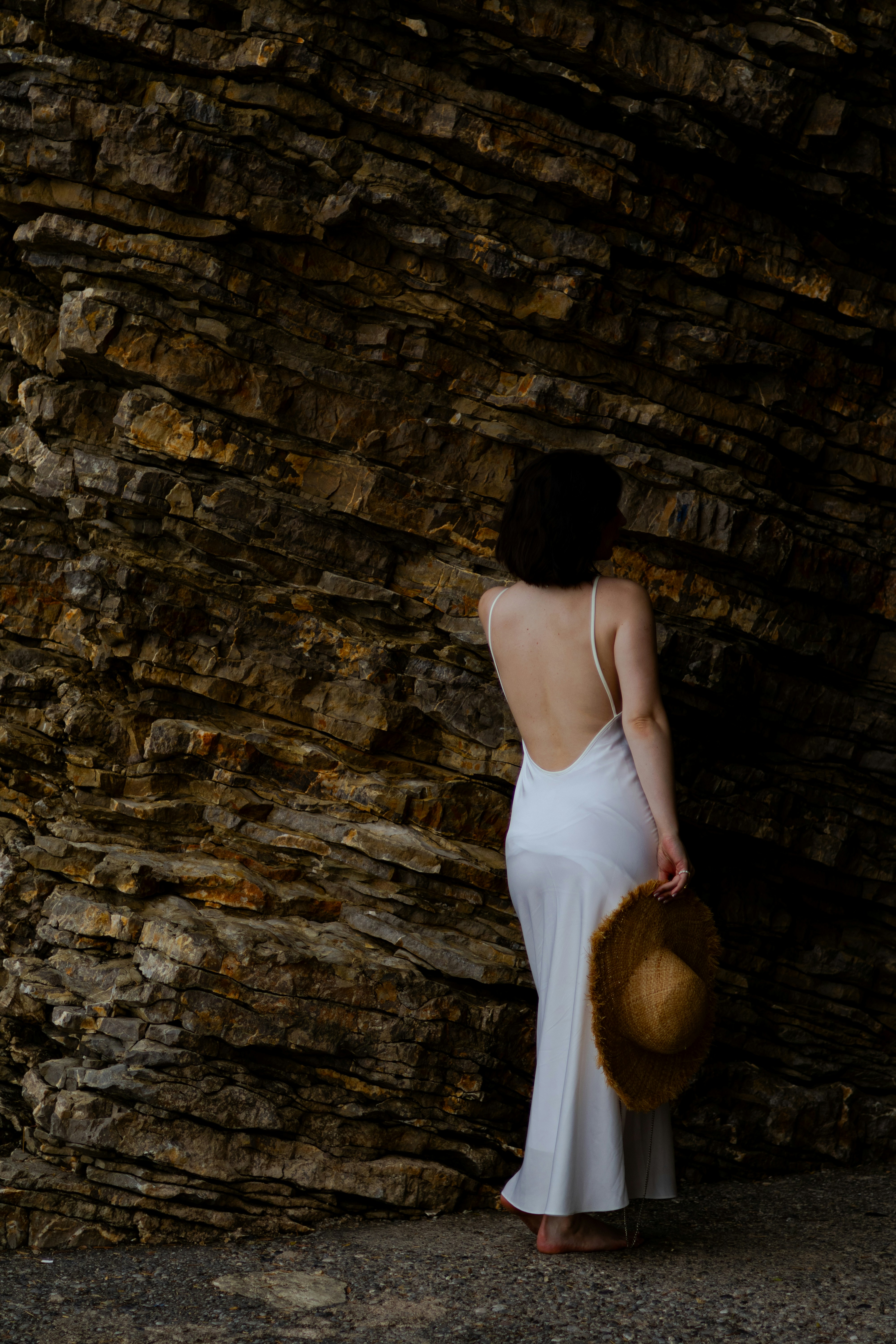 Una mujer con un vestido blanco de pie junto a un muro de piedra foto ...