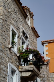 A stone building with a balcony with flowers on it