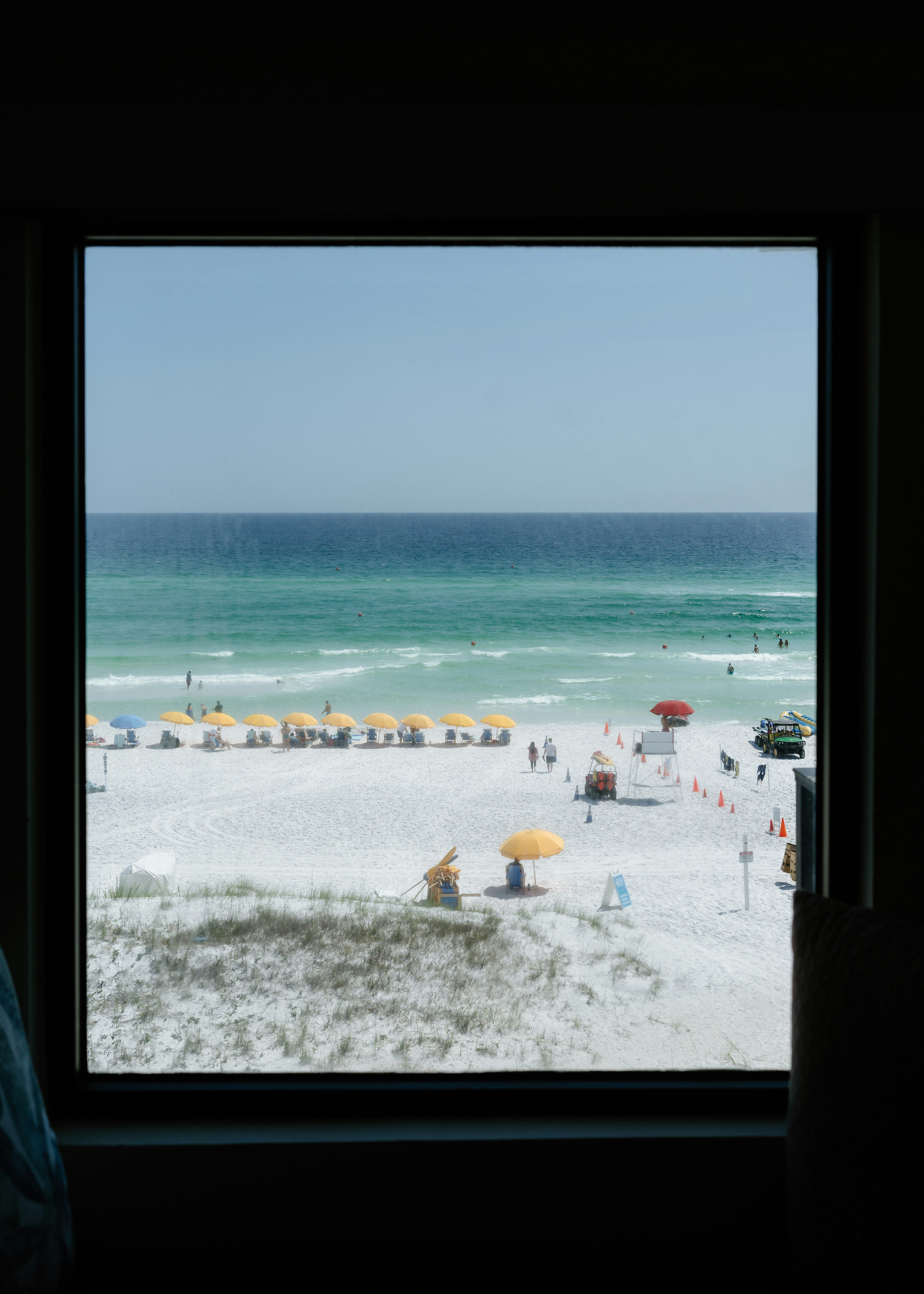 A person looking out a window at a beach
