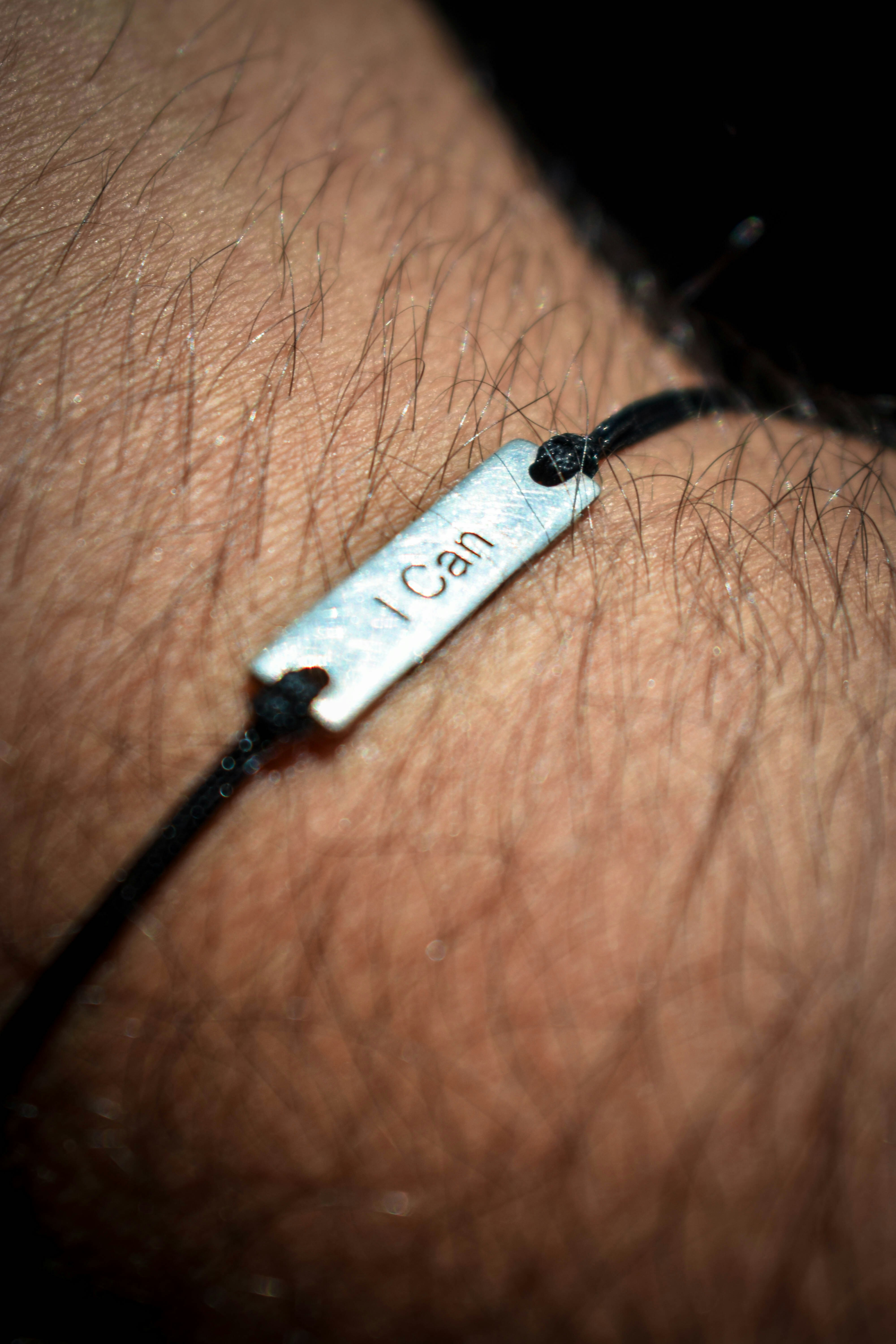 A man's arm with a bracelet with a name tag on it