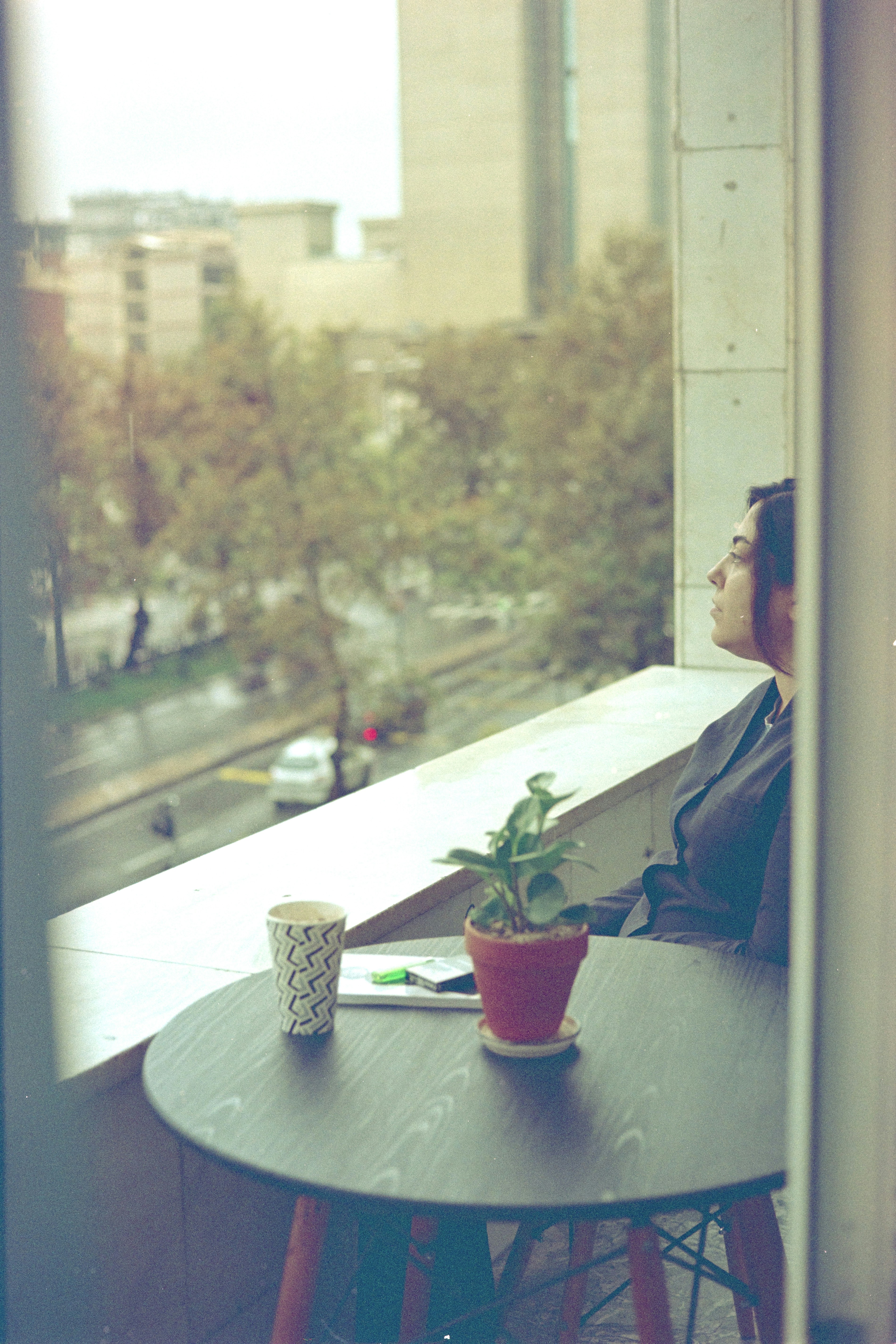 A woman sitting at a table looking out a window
