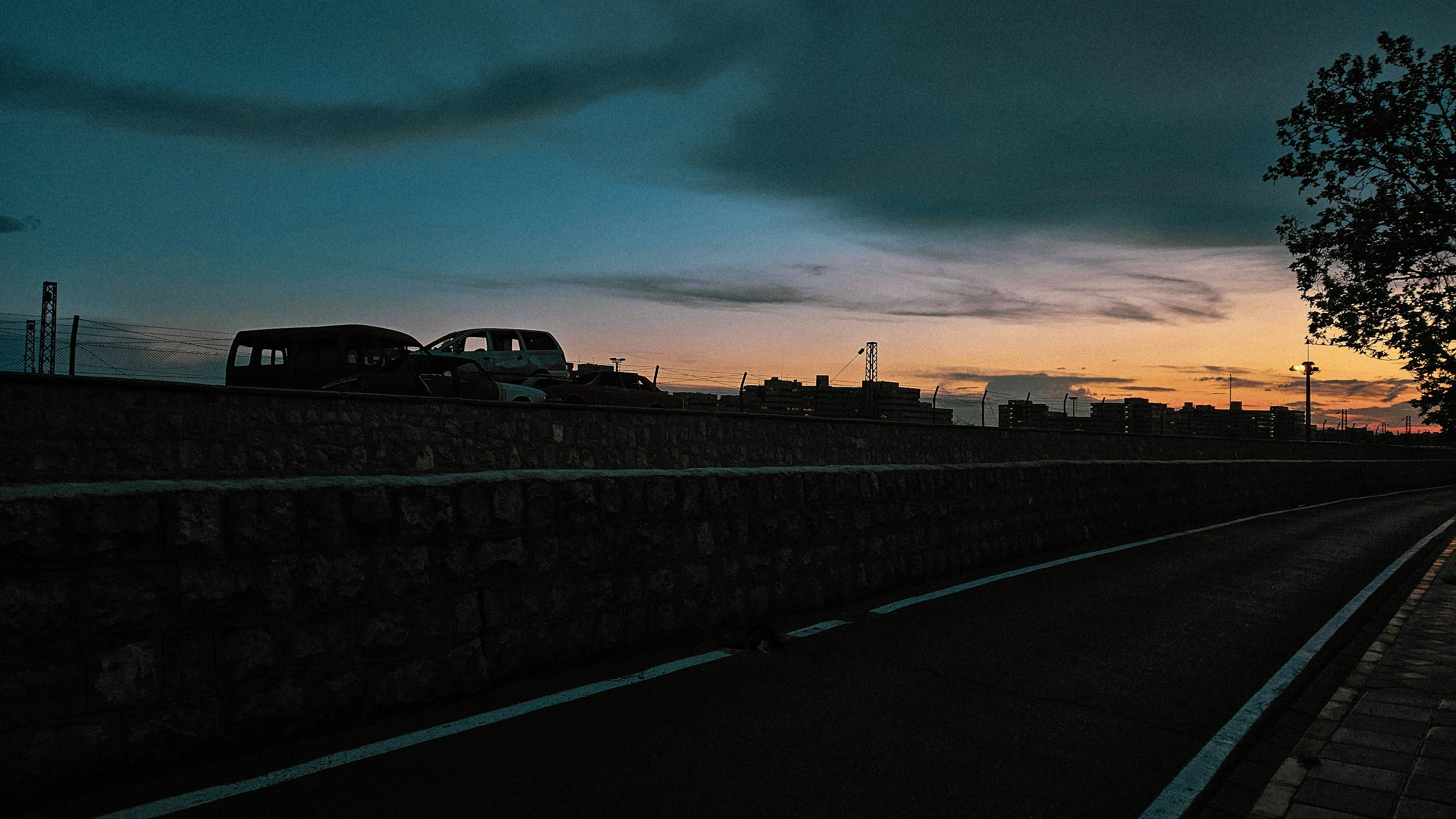 A long road with a tree and a sky in the background