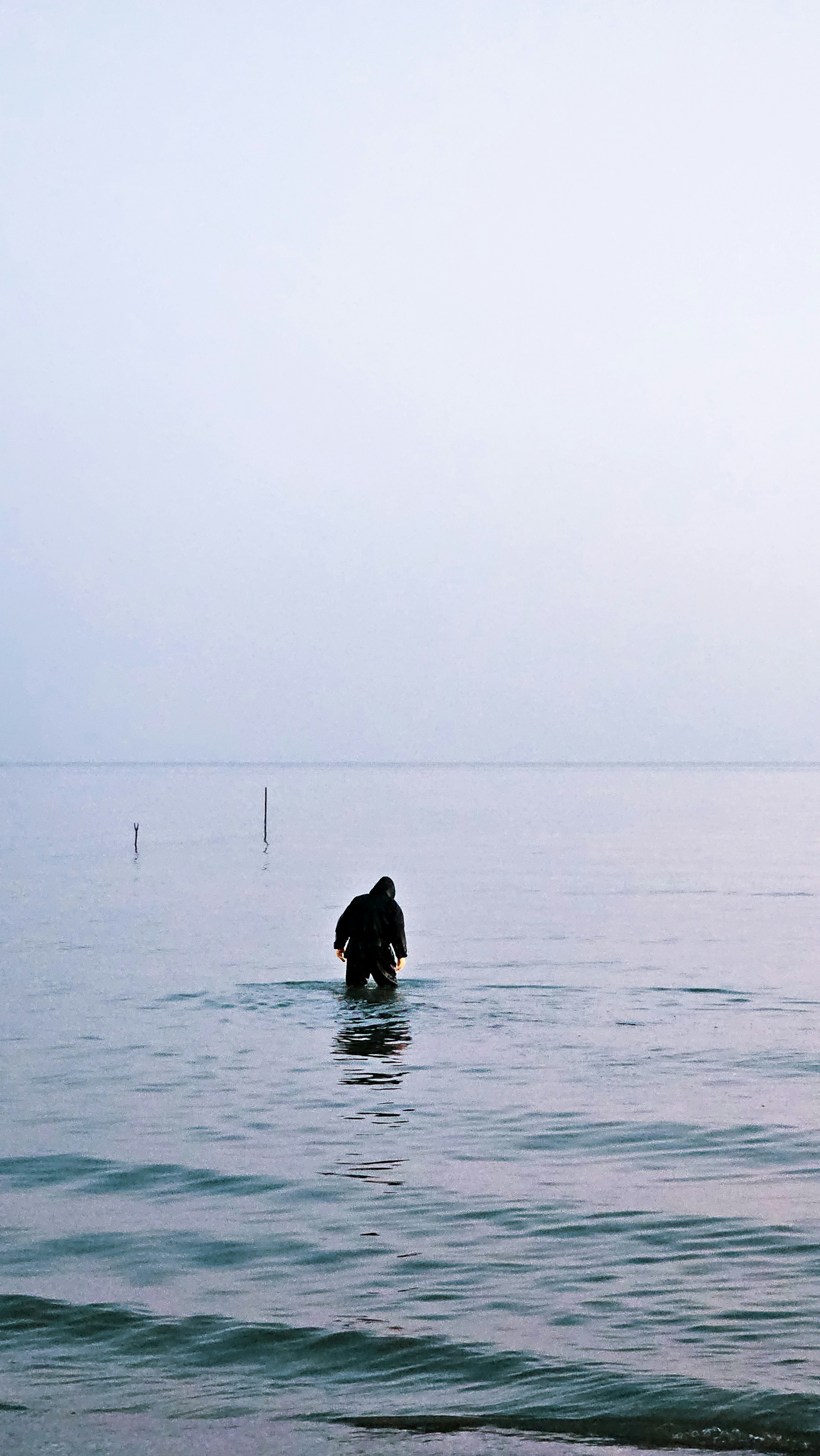 A person standing in the water on a surfboard