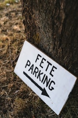 A white sign that is on the side of a tree