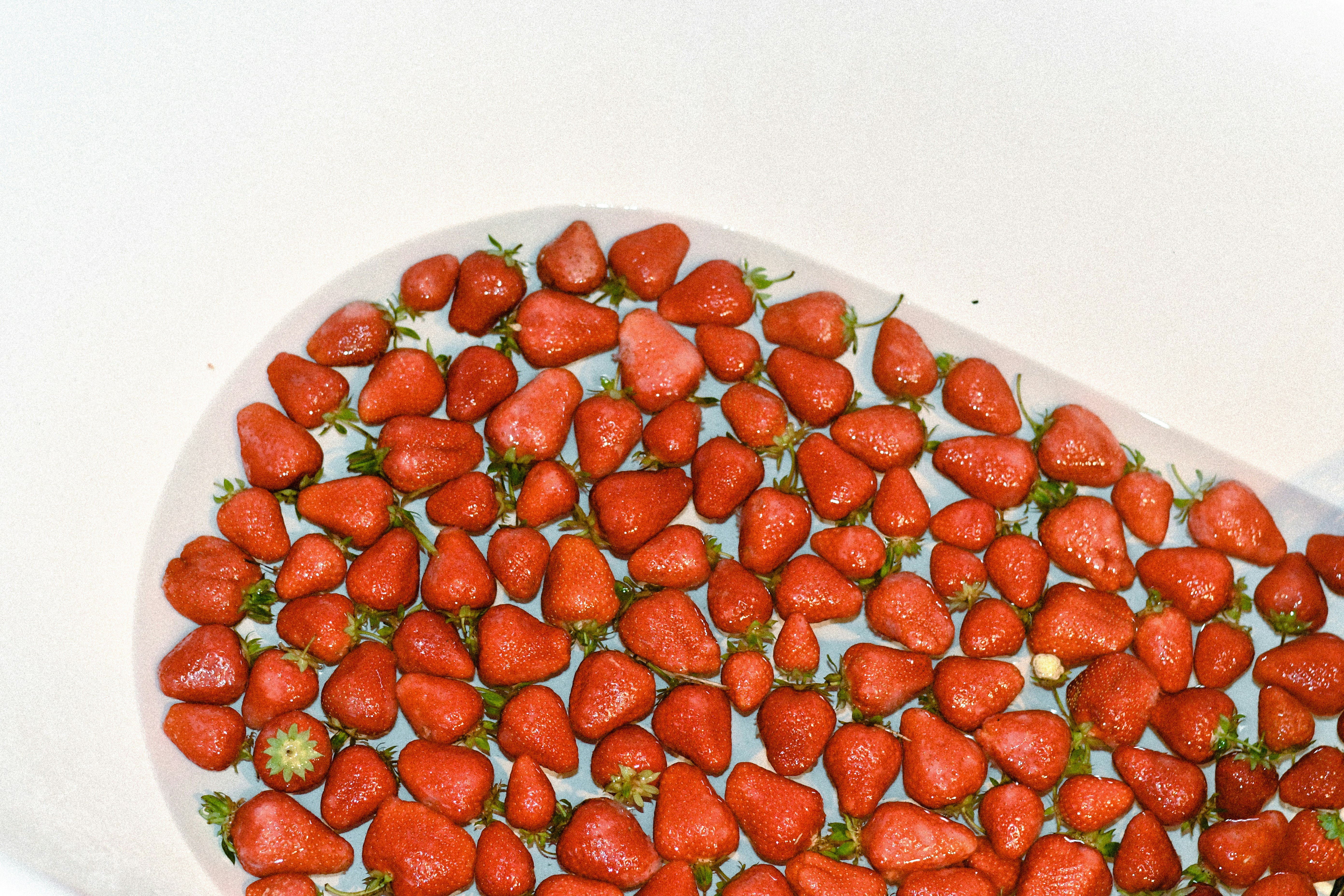 A heart shaped bowl filled with strawberries on top of a table