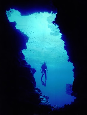 A person in a wet suit swimming in a cave