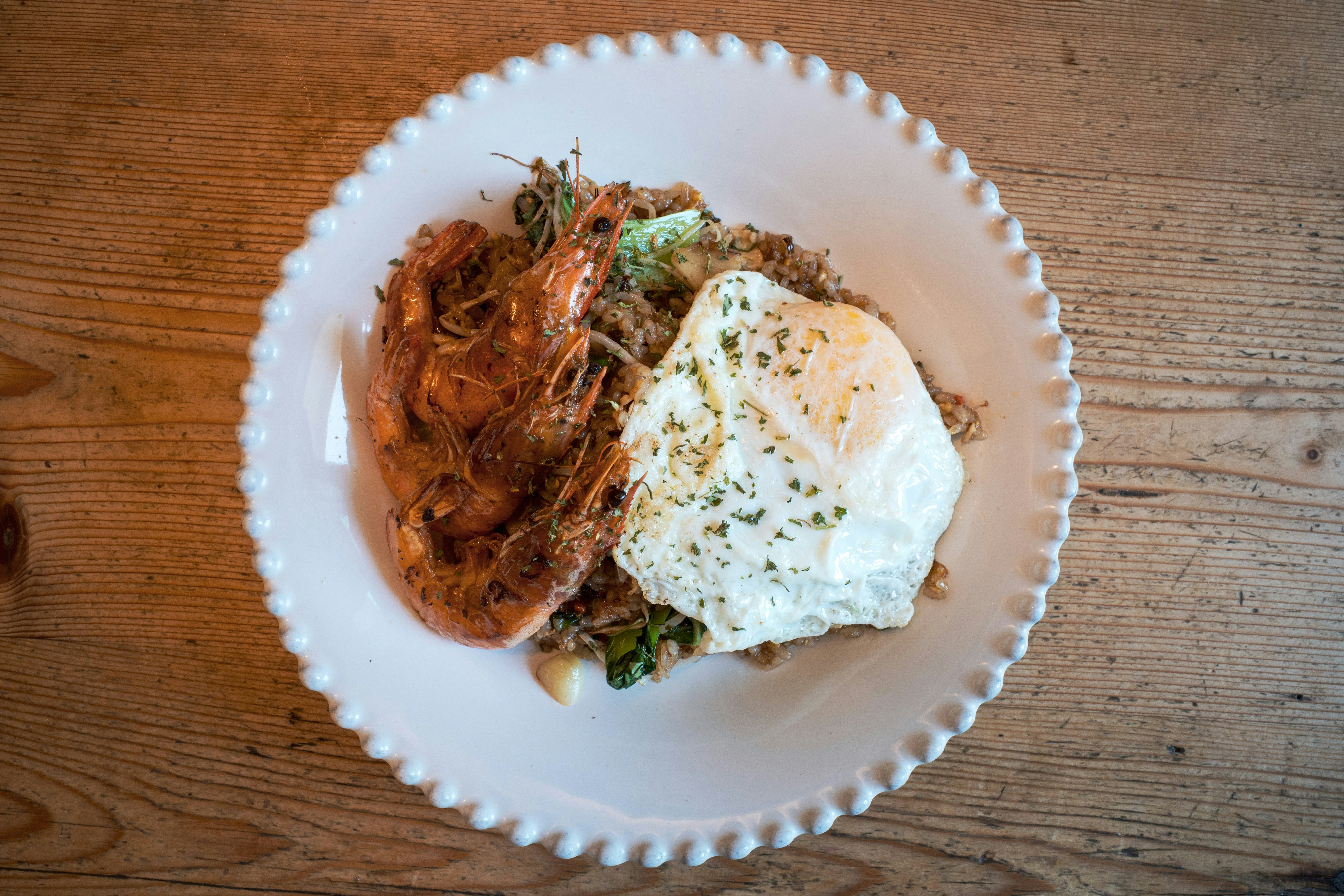 Noodles with a fried egg on a scalloped white plate
