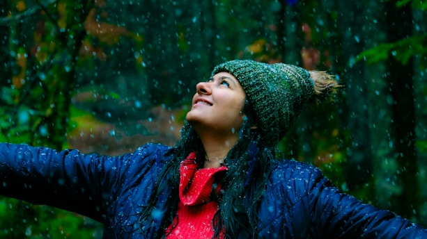 A woman standing in the rain with her arms outstretched