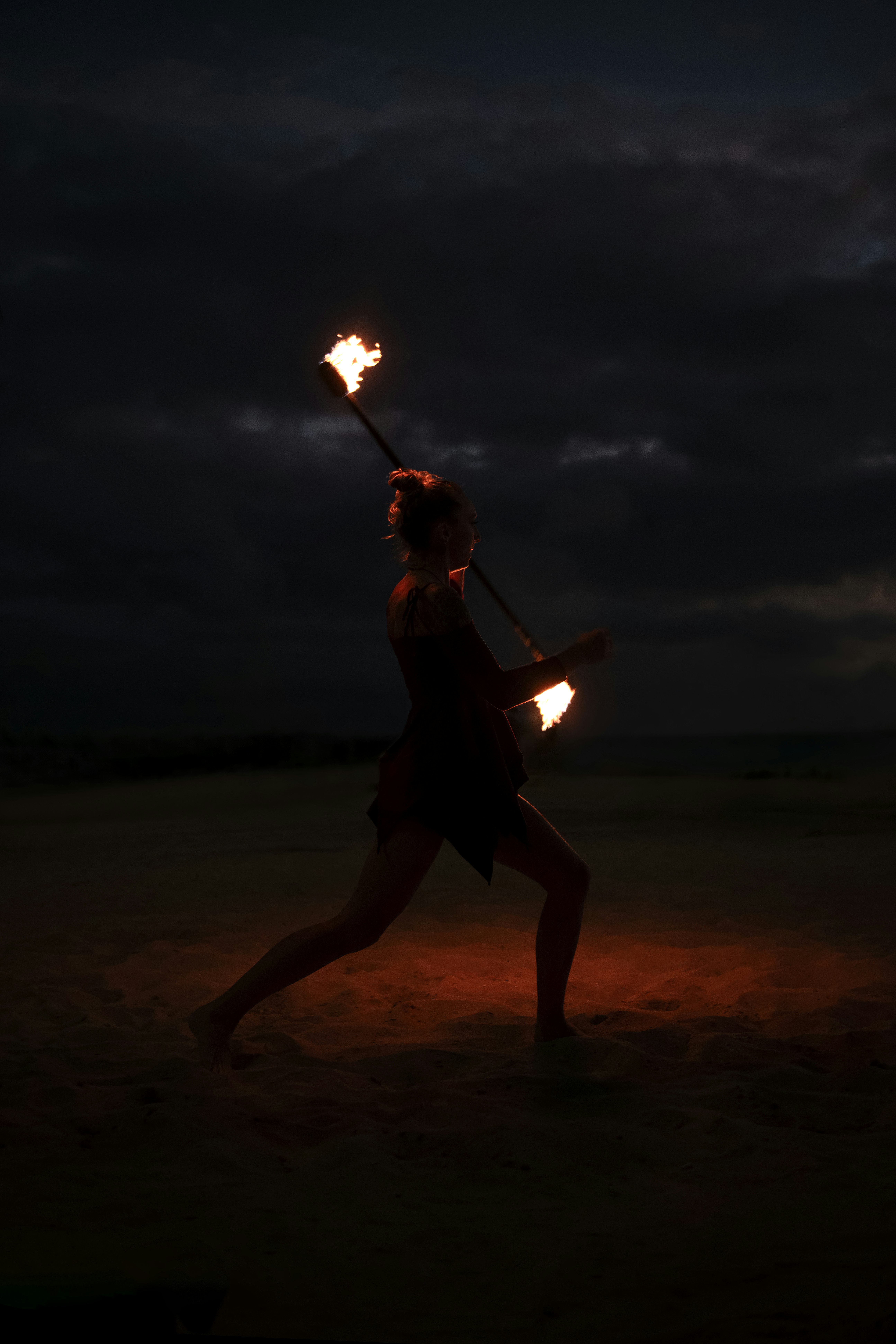 A woman holding two torches in the dark