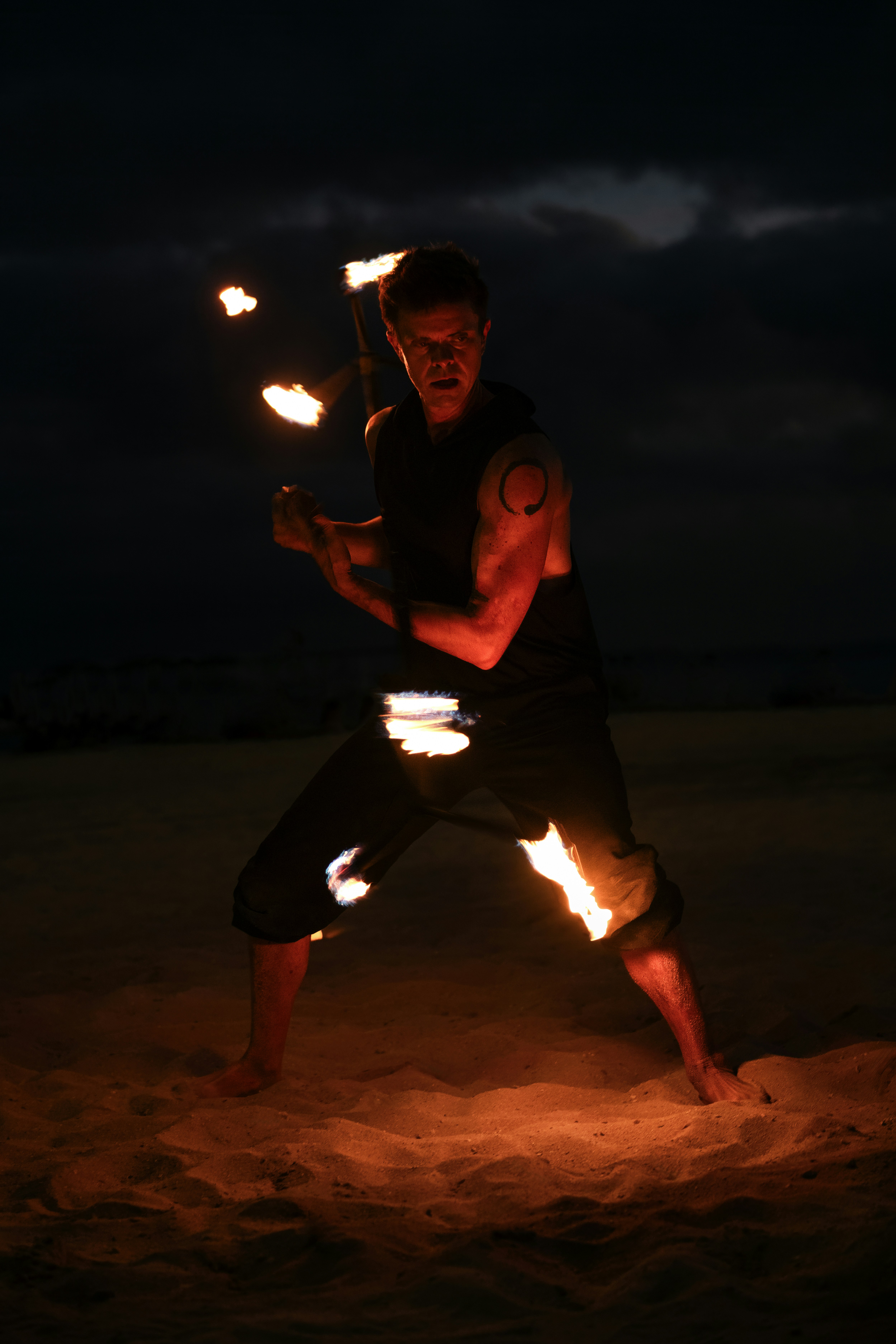 A man standing on a beach holding two torches
