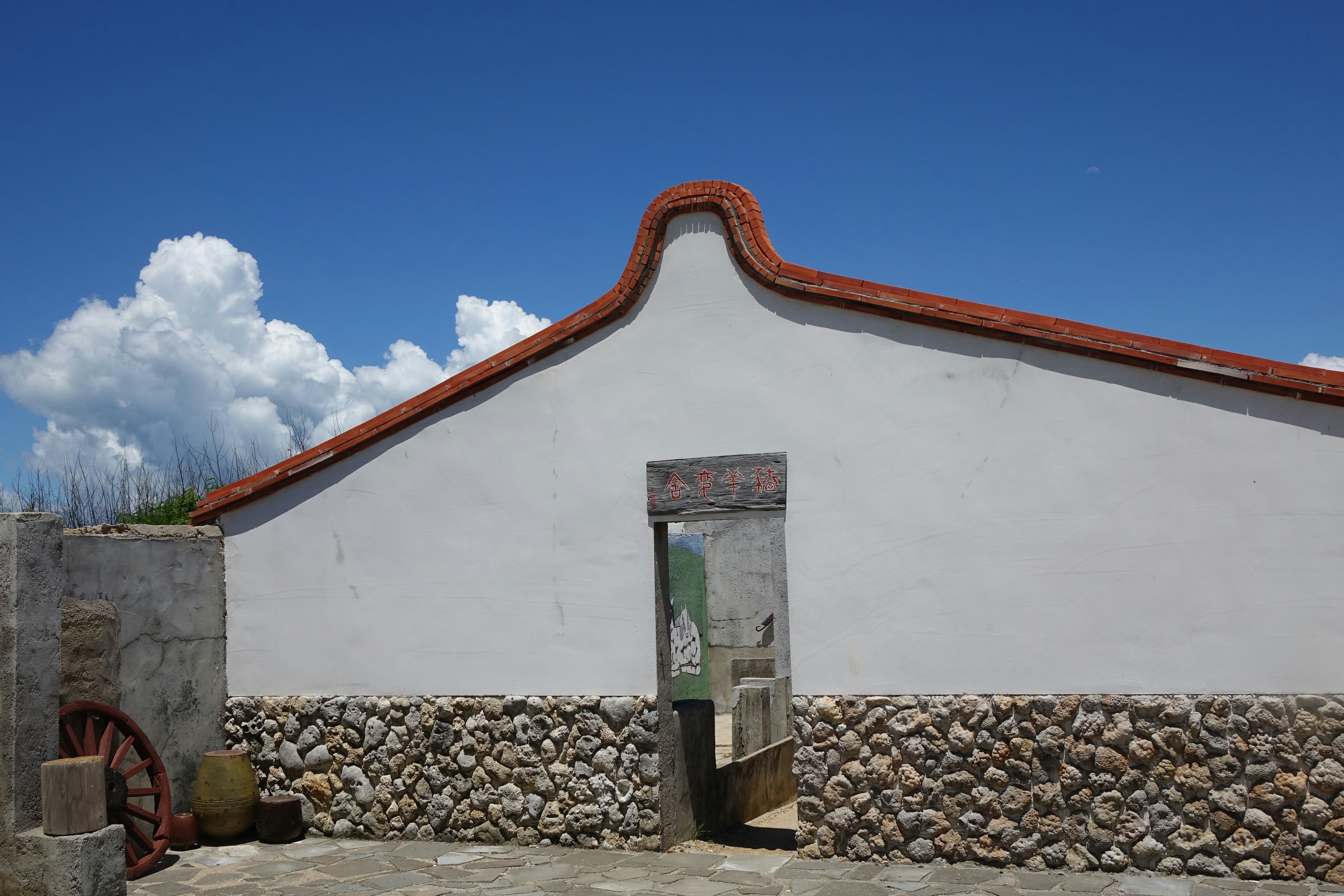 A white building with a red roof and a green door