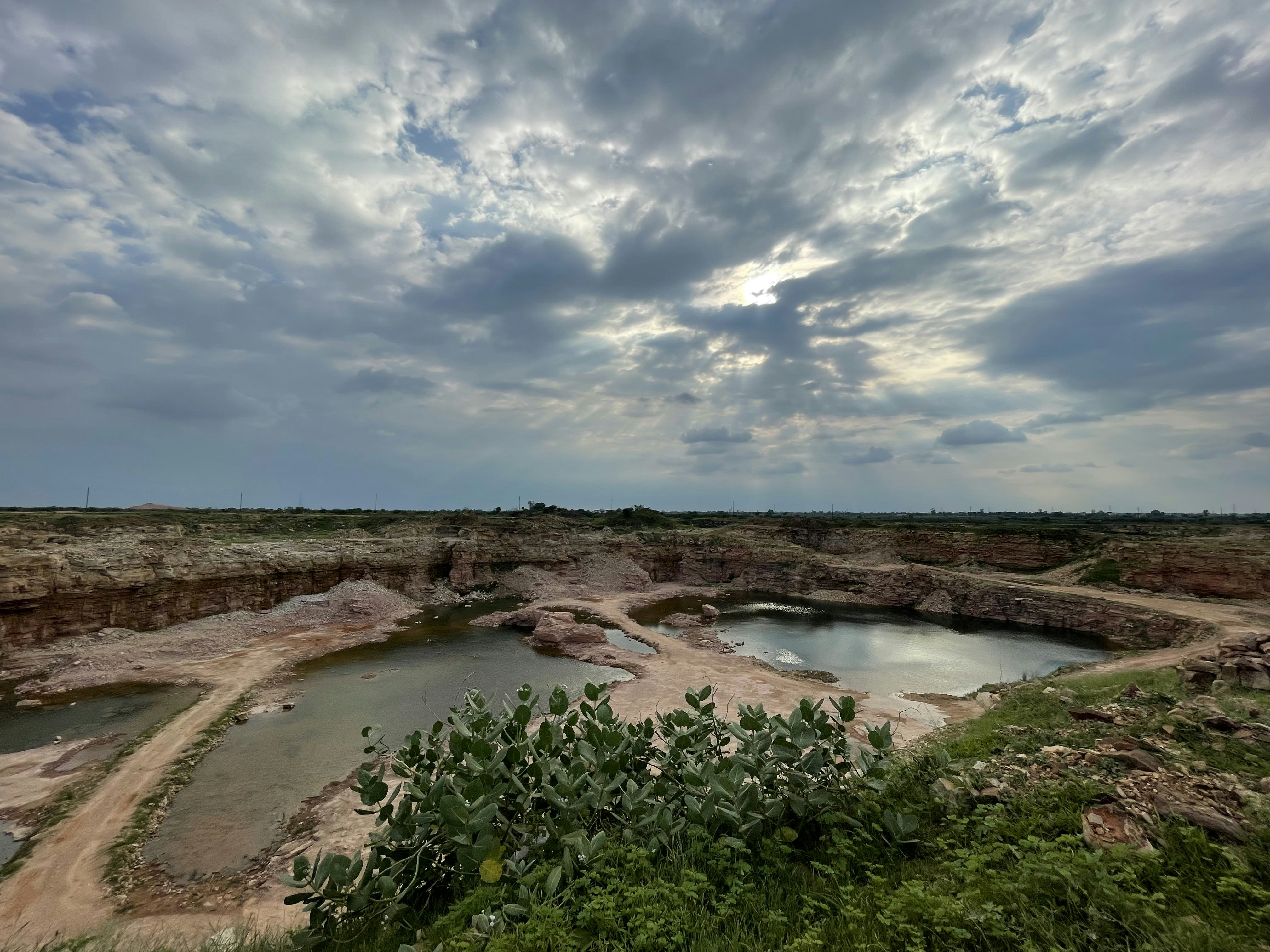 Aerial view of quarry from above, dark atmospheric overcast sky, deep shadows on rocky terrain