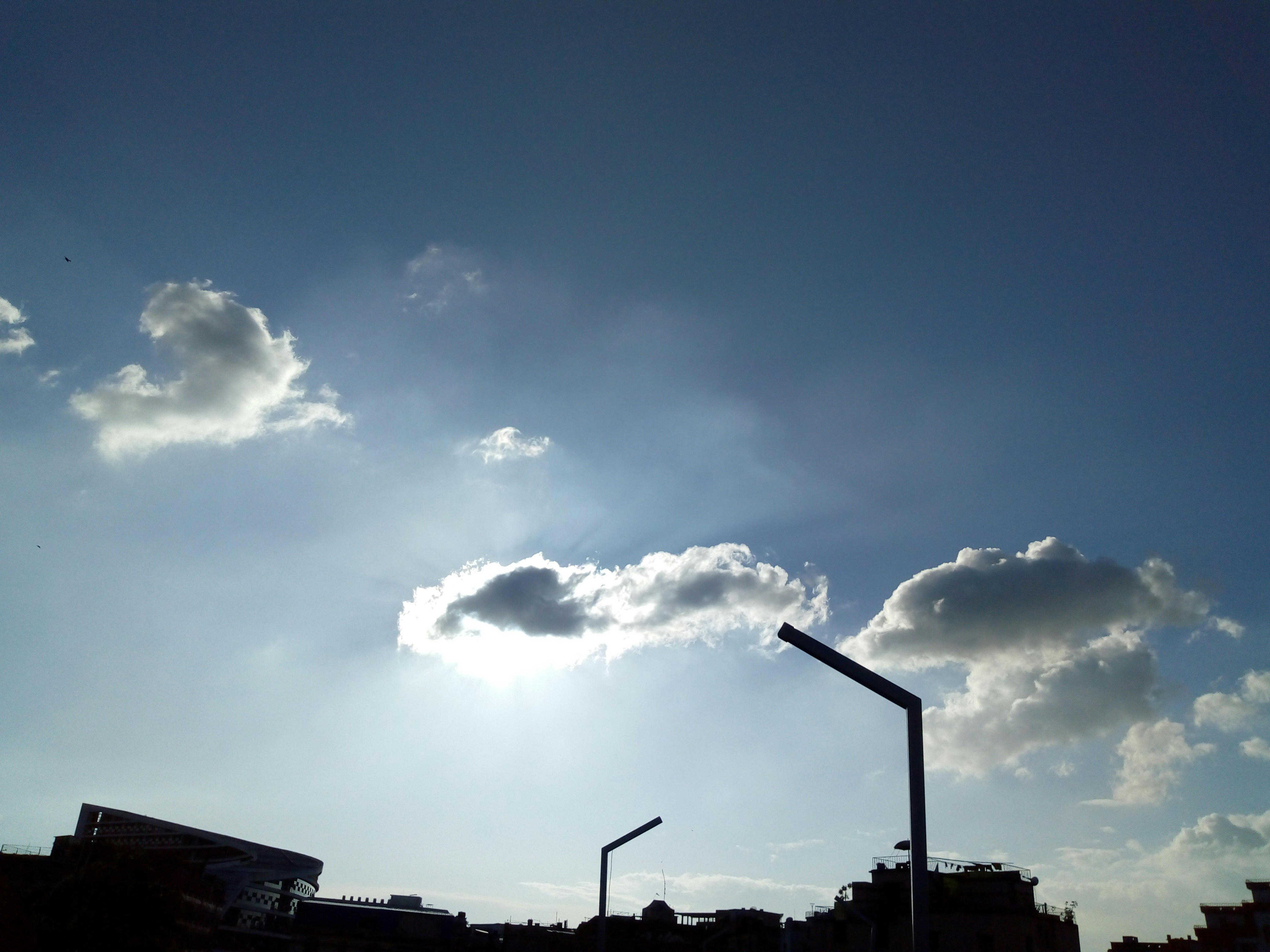 The sun is shining through the clouds in the sky