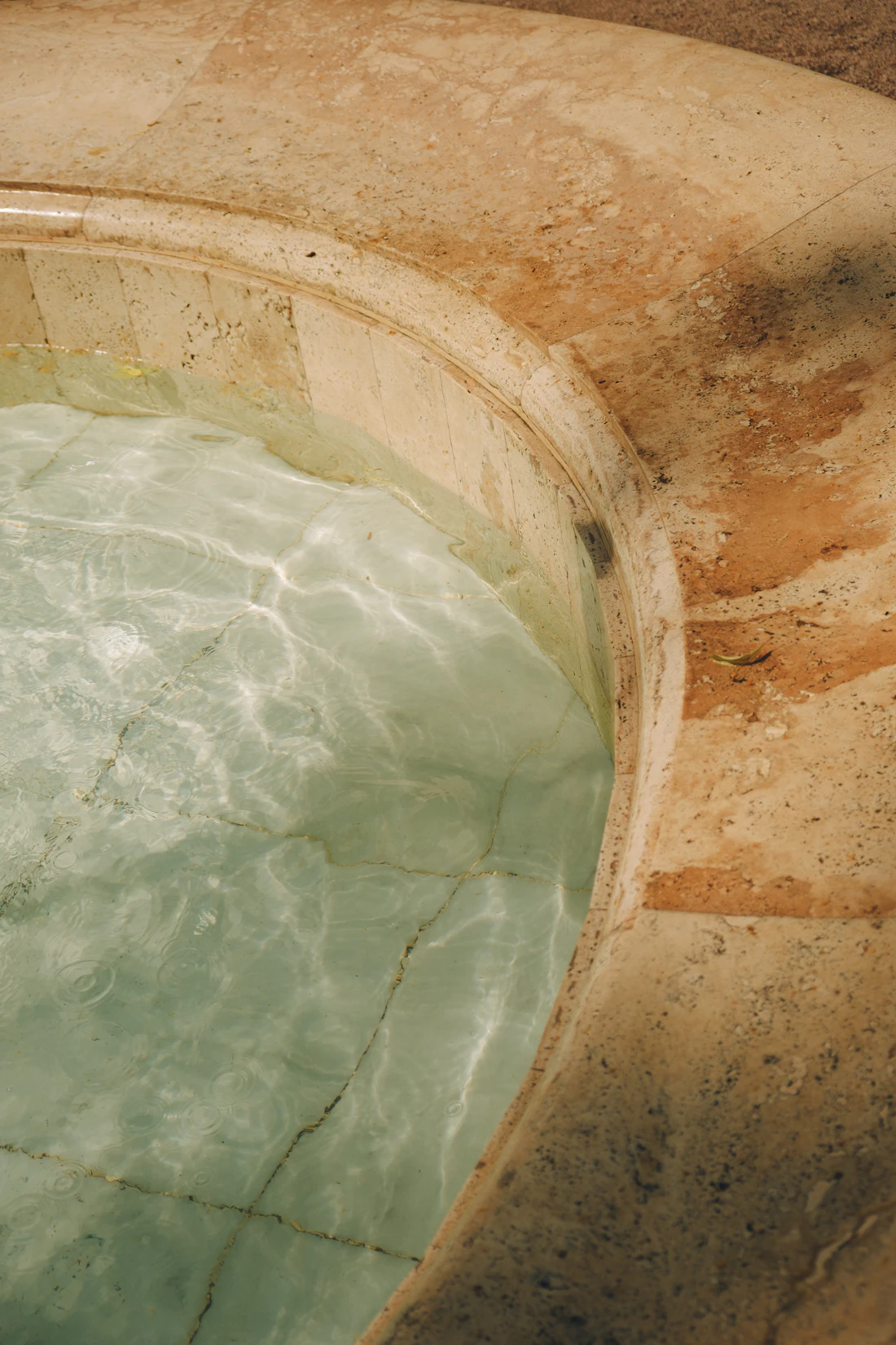 Vasque creusée dans une pierre couleur miel, eau claire et translucide