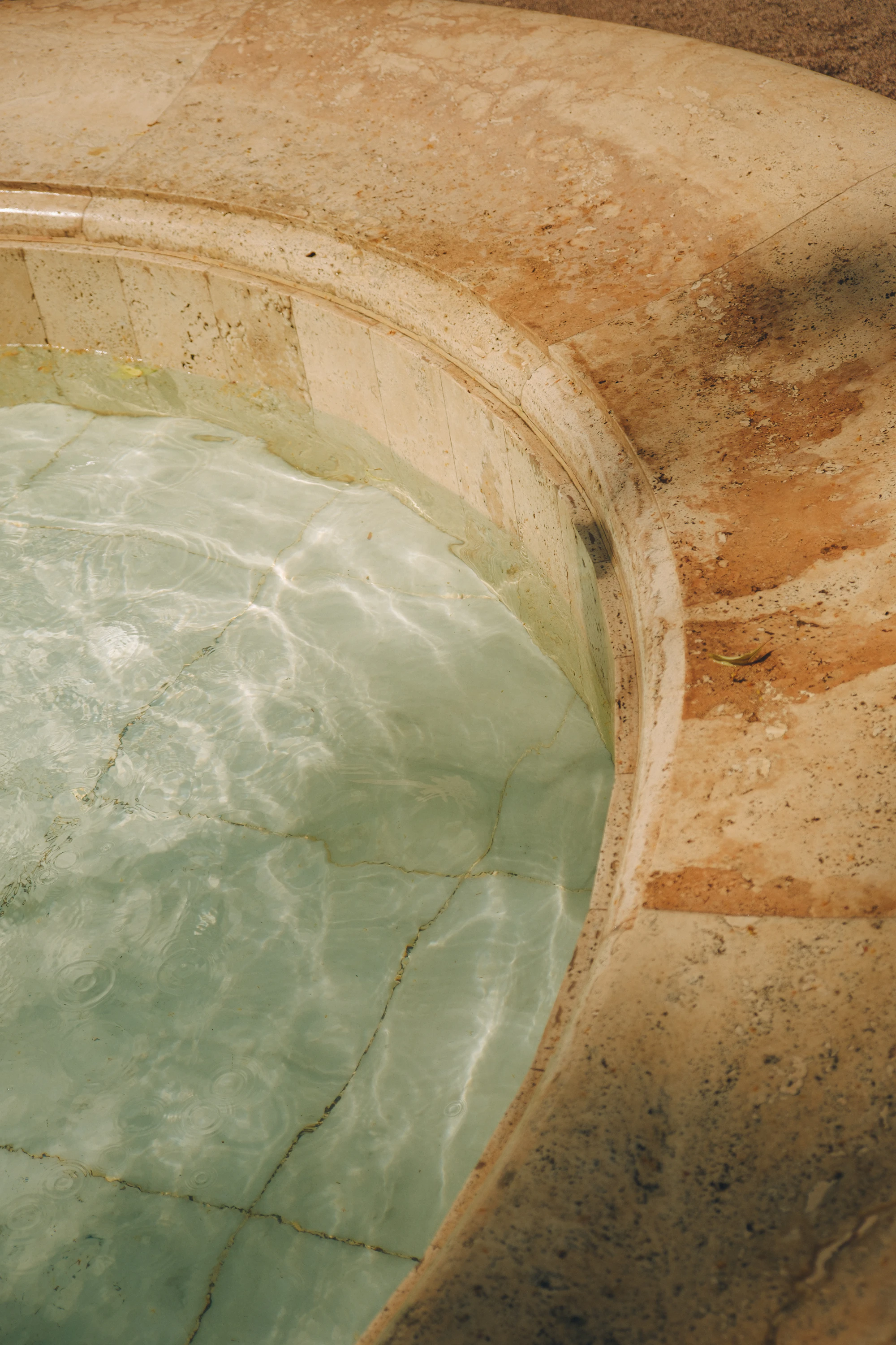 Vasque creusée dans une pierre couleur miel, eau claire et translucide