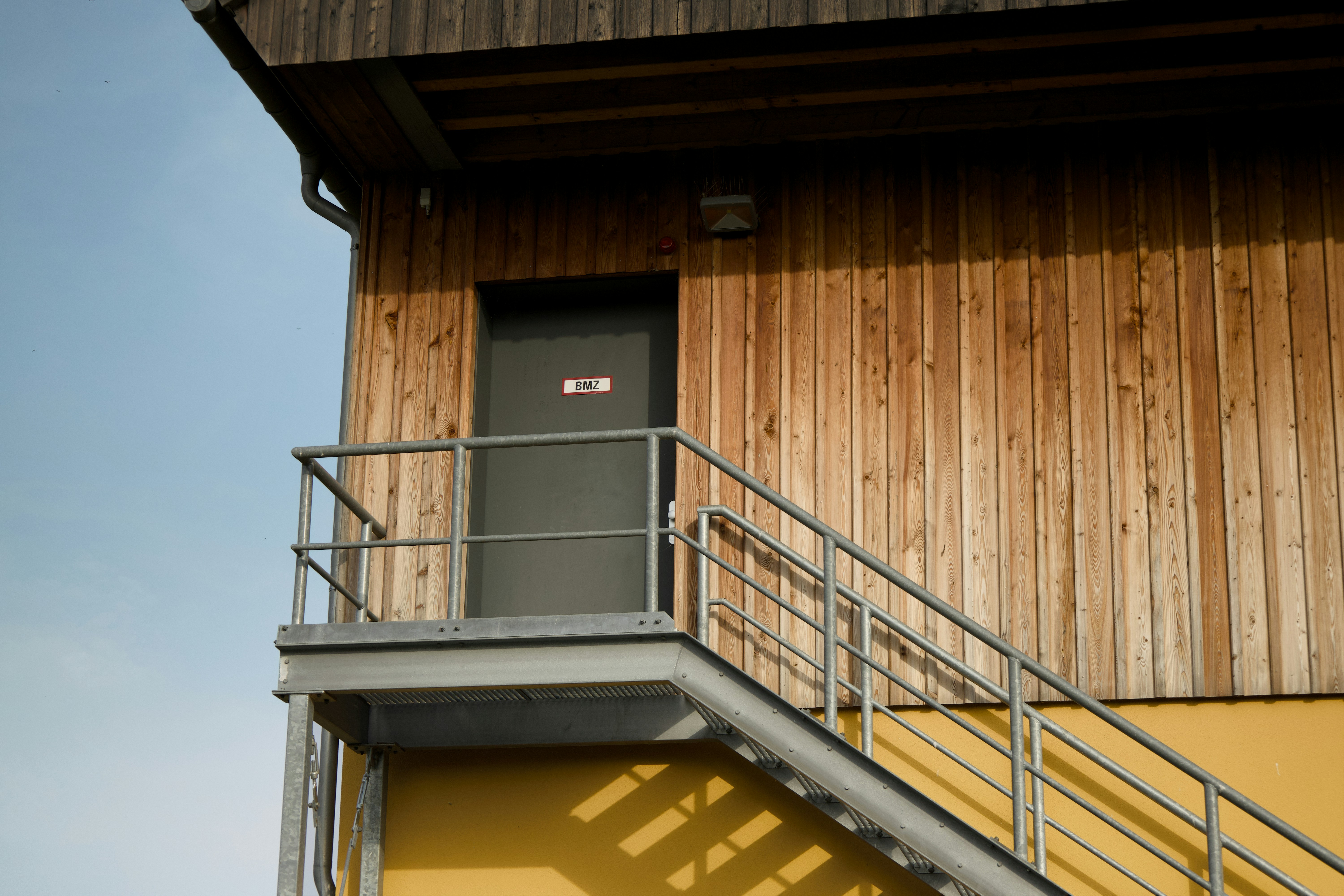 A tall wooden building with a metal hand rail