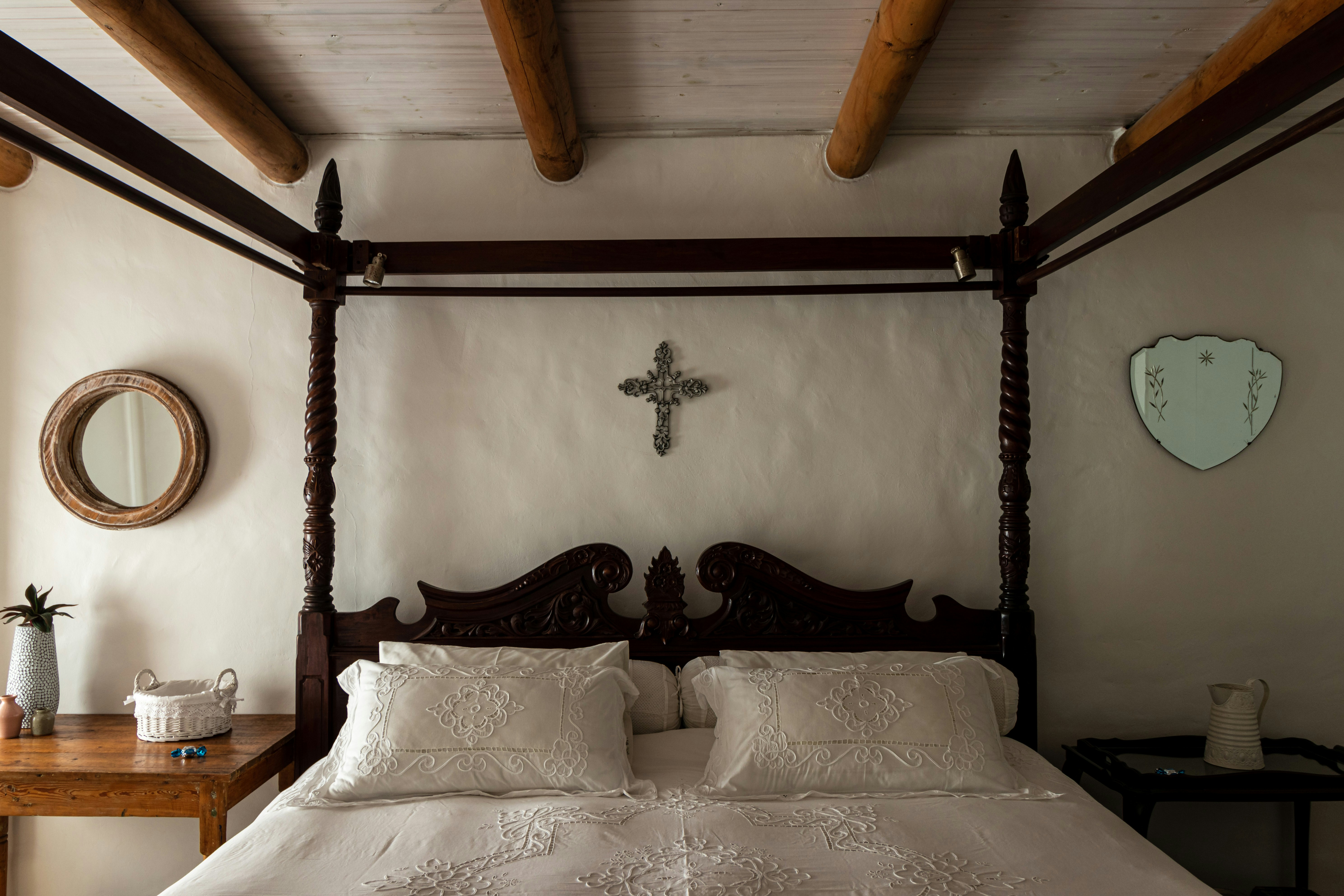 A bed with a cross on the wall above it