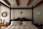 A bed with a cross on the wall above it