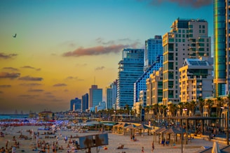 A crowded beach with tall buildings in the background