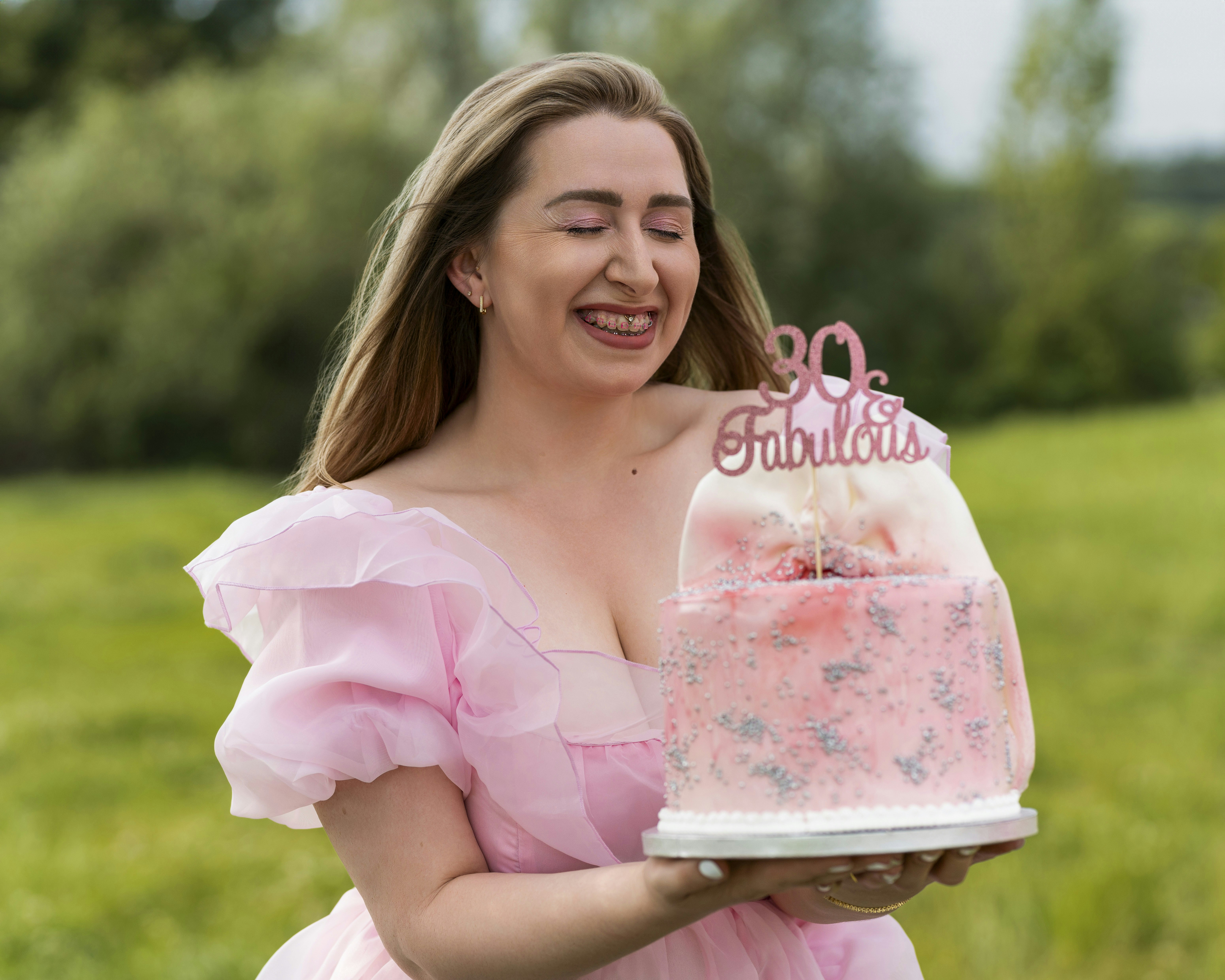 Eine Frau in einem rosa Kleid hält einen Kuchen in der Hand
