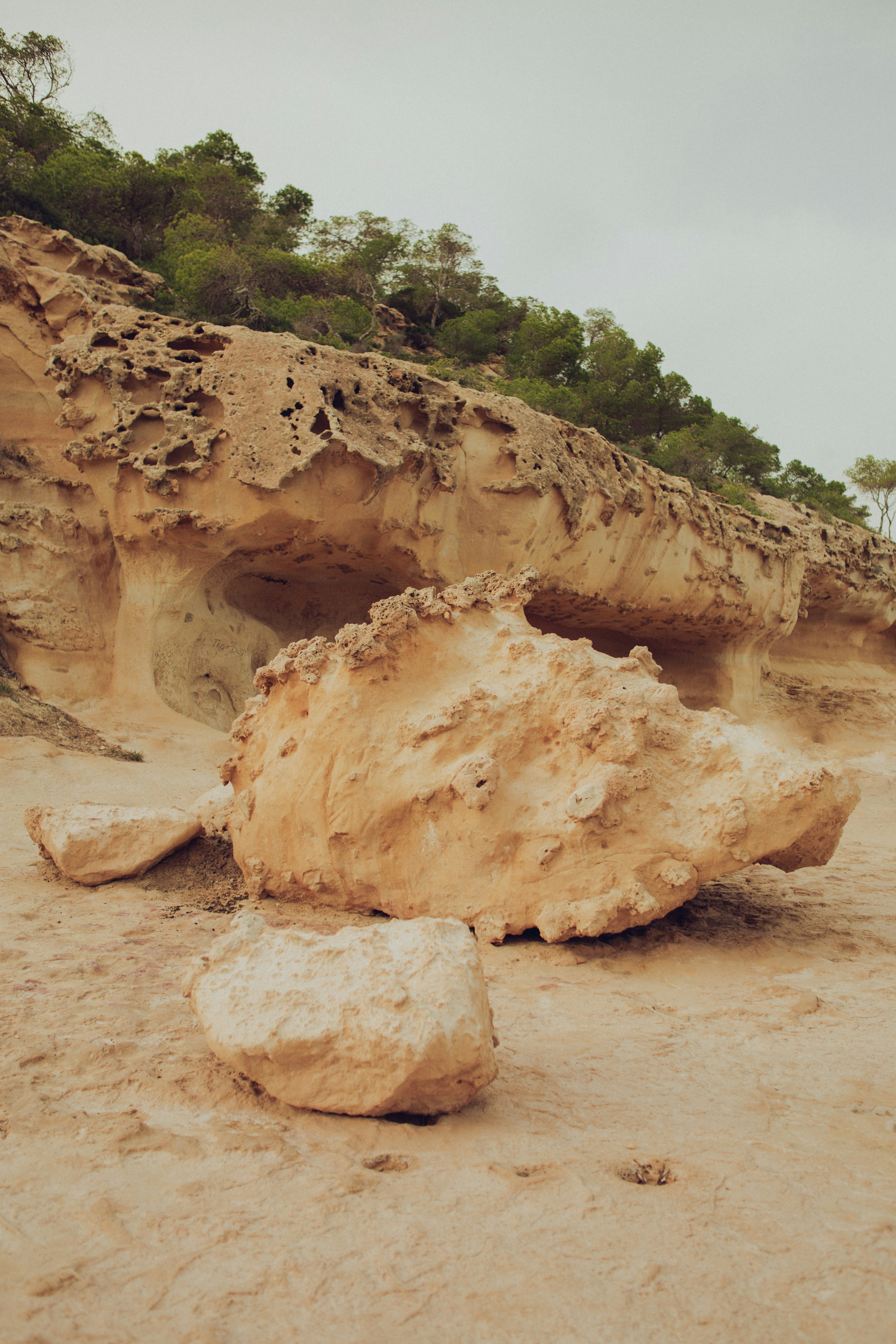 A large rock sitting on top of a sandy beach
