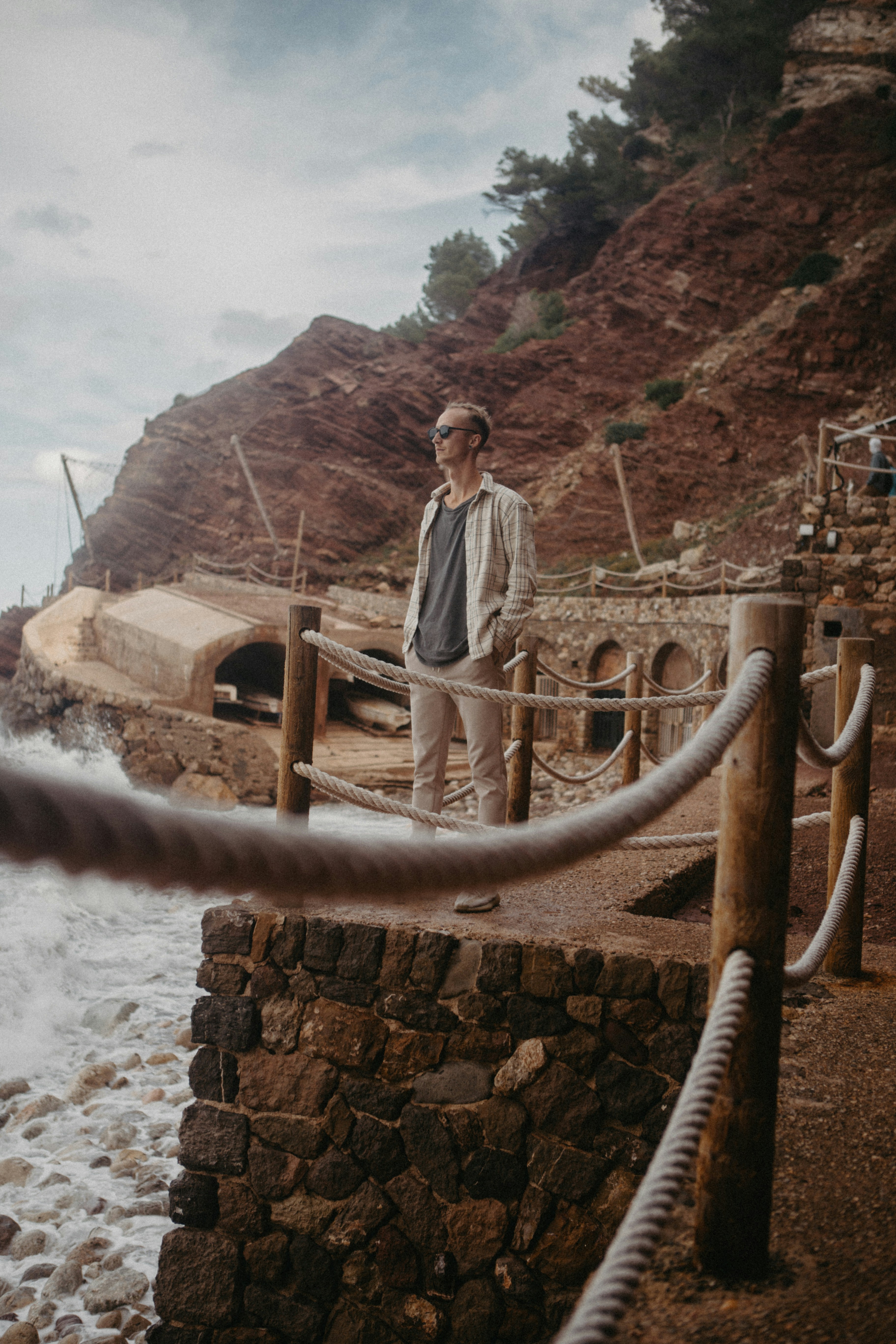 A man standing on a pier next to a body of water