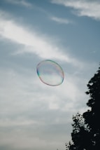 A soap bubble floating in the air near a tree