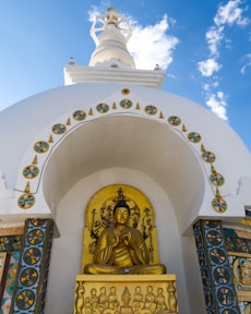 A golden buddha statue in front of a white building