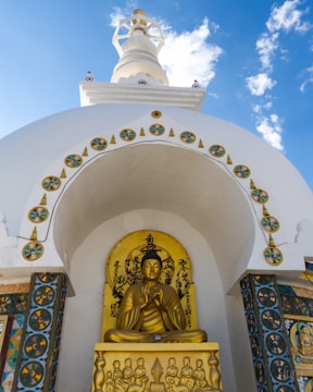 A golden buddha statue in front of a white building