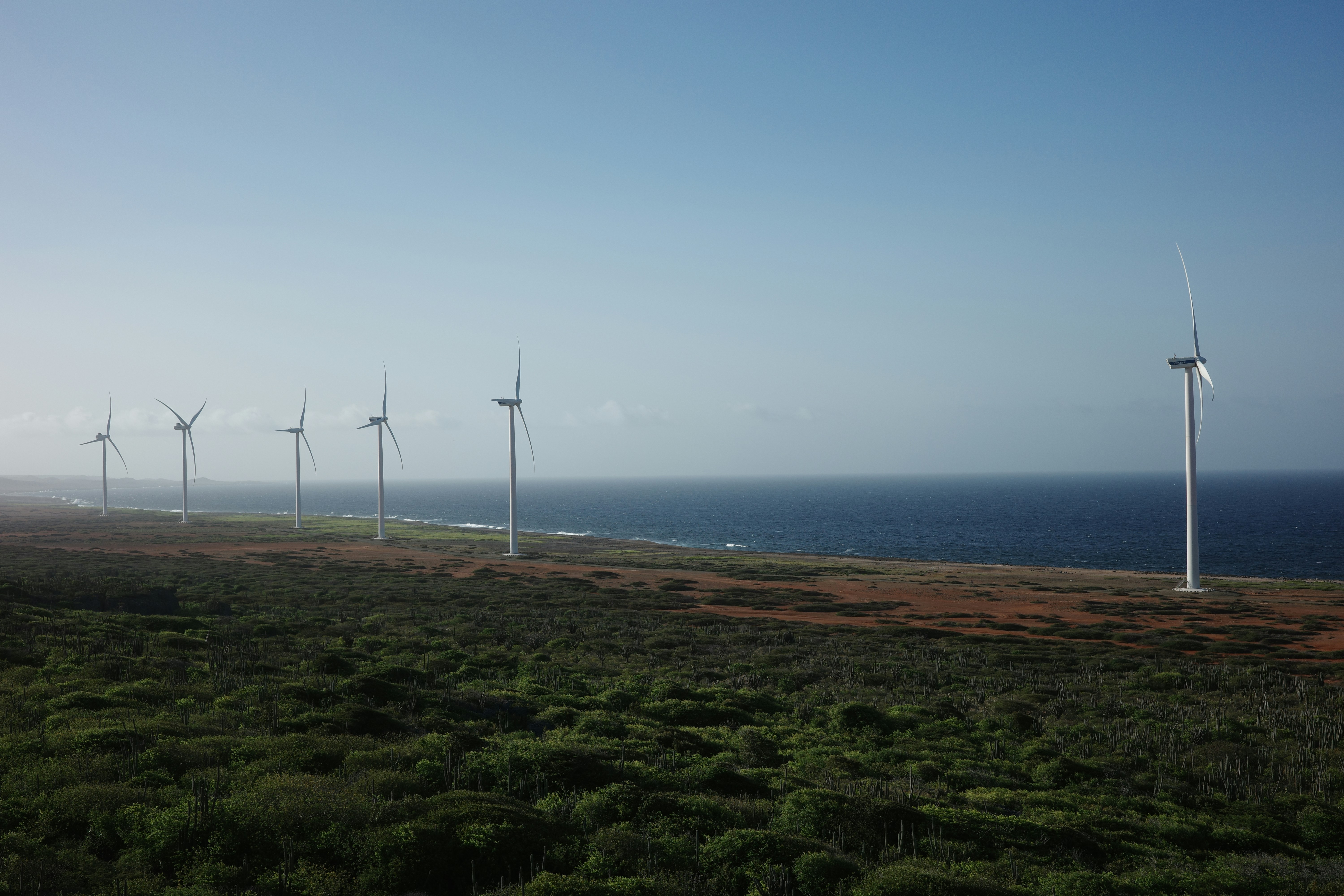 Eine Reihe von Windmühlen auf einem grasbewachsenen Hügel in der Nähe des Ozeans
