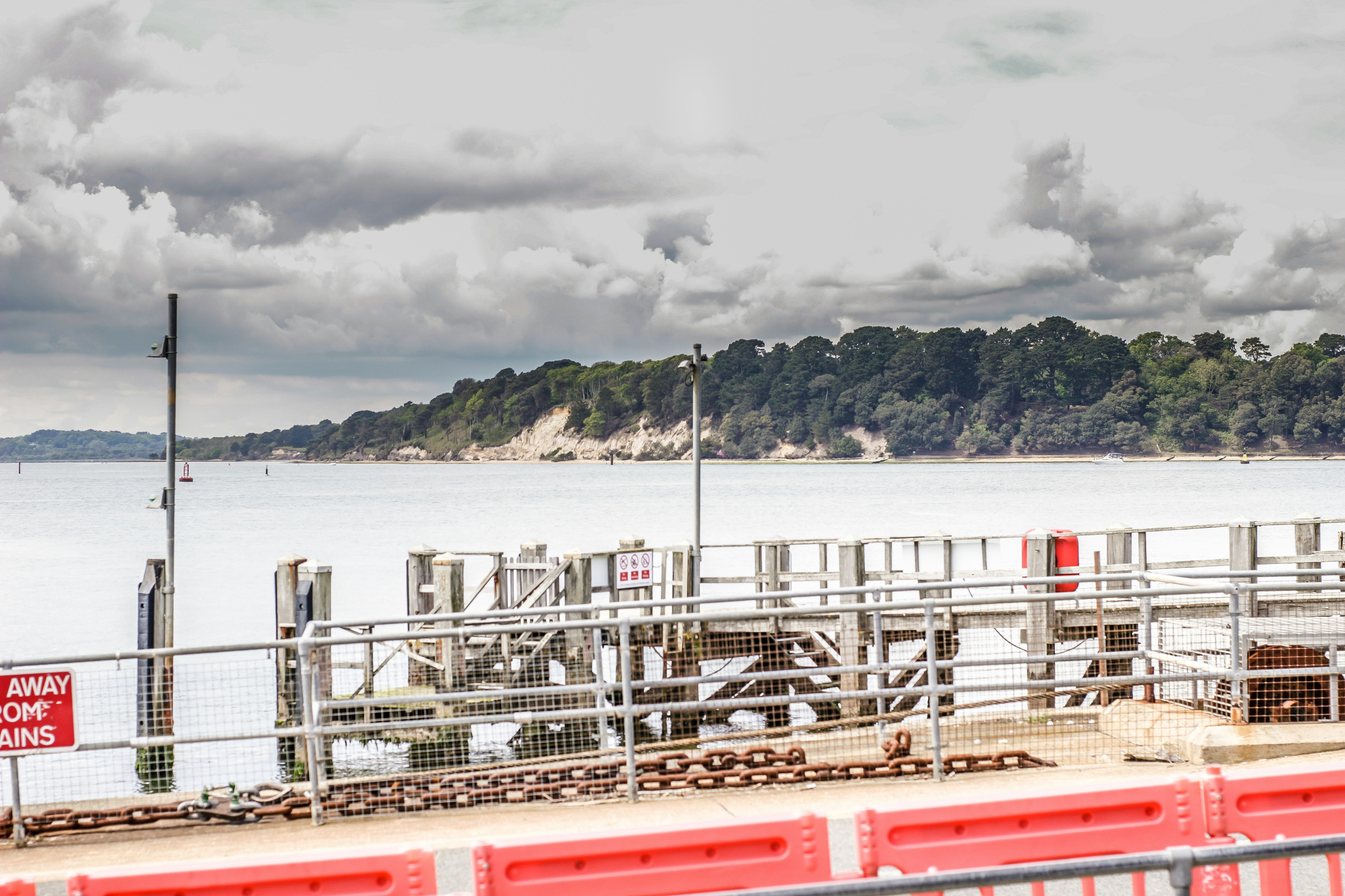 A red and white train traveling past a large body of water