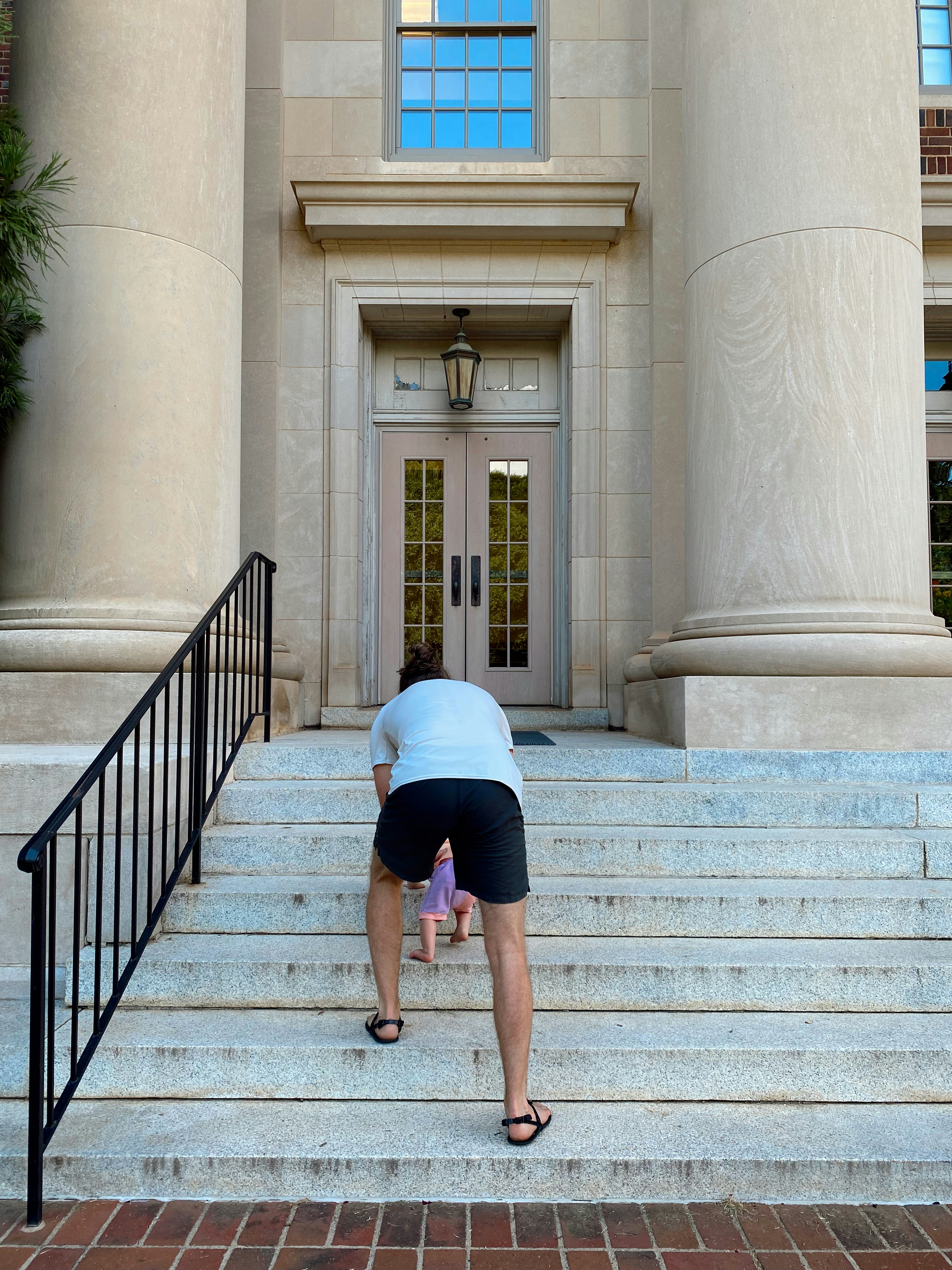 Eine Person, die sich auf den Stufen eines Gebäudes bückt